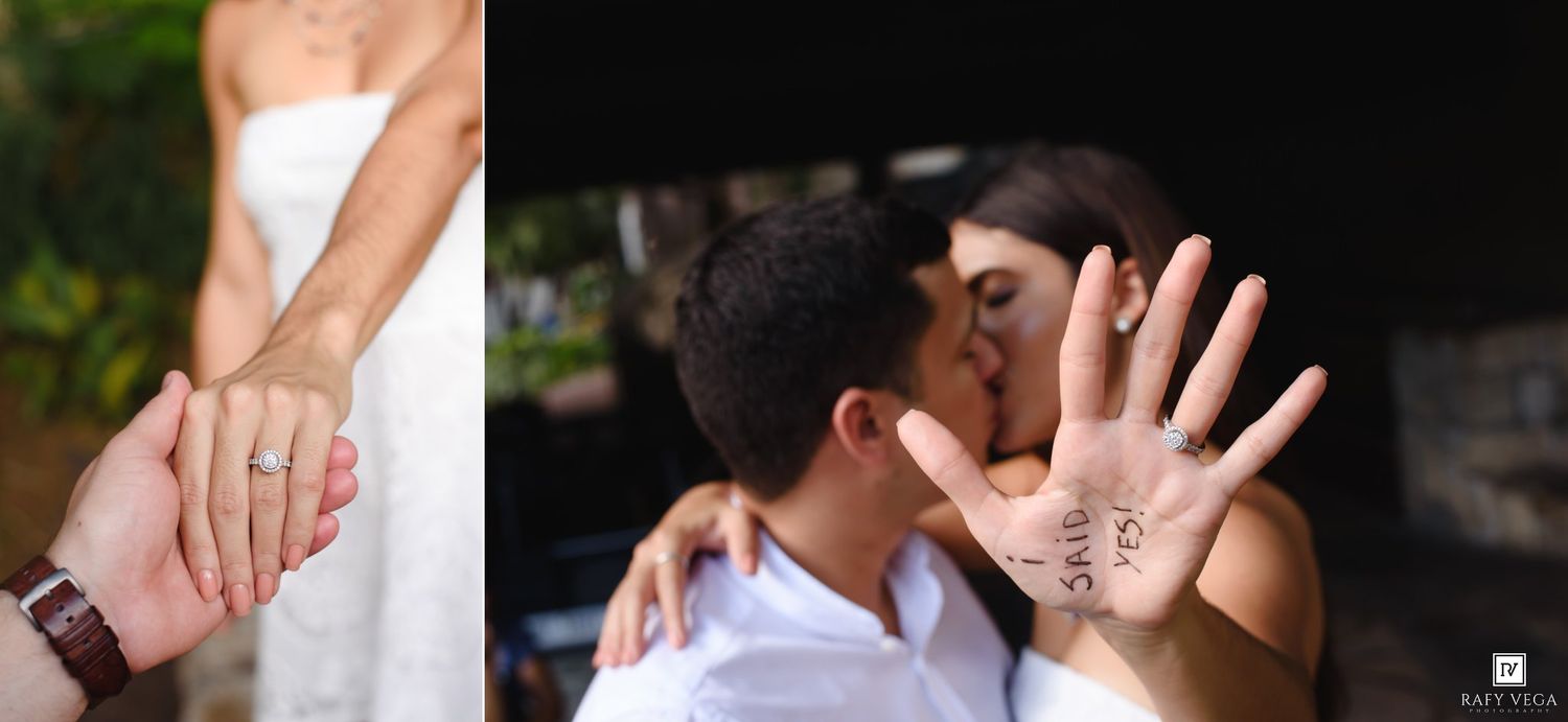 Couple sharing a kiss at their engagement shoot, showcasing a diamond ring and handwritten wedding date on palm.