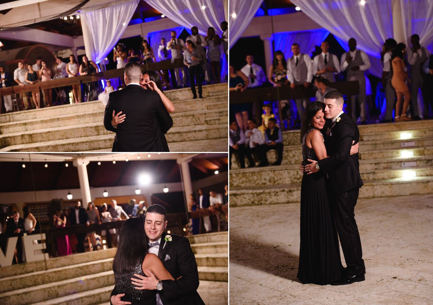 Couple sharing romantic first dance at elegant outdoor wedding reception with blue lighting and guests watching.