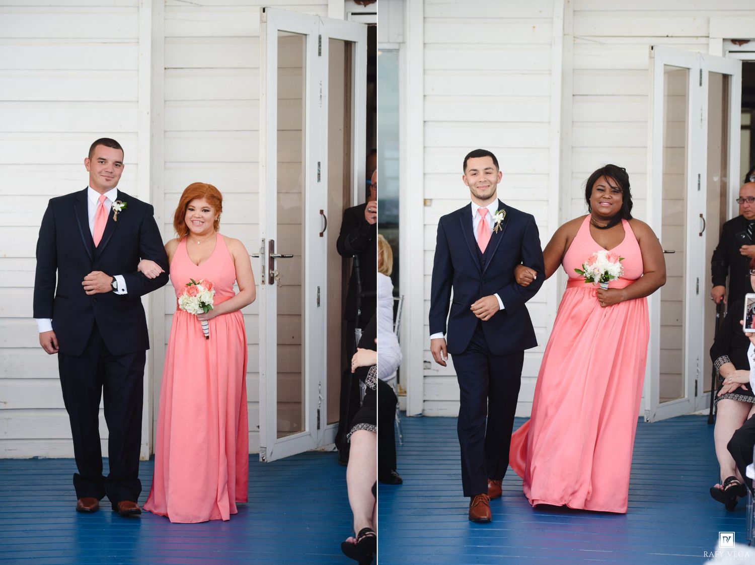 Bridesmaids in coral gowns walk with groomsmen in navy suits during a wedding processional at a white venue.