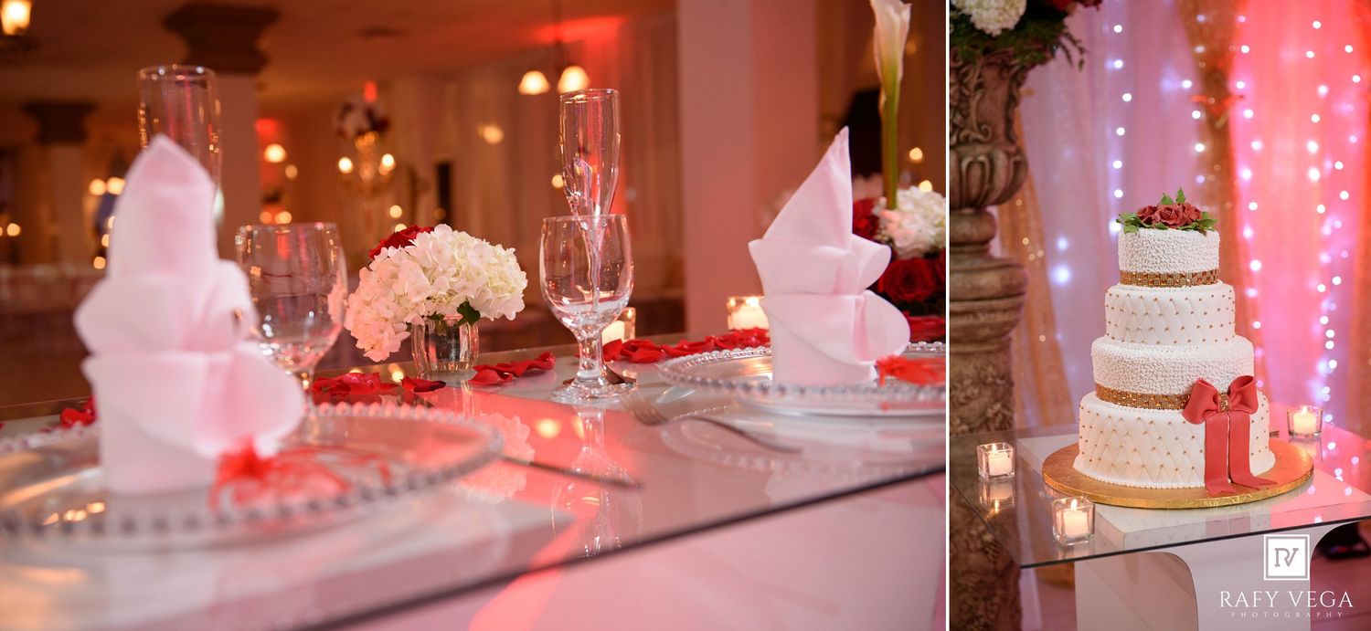 Elegant wedding reception table with white cake, champagne flutes, floral centerpieces, and red accents in a decorated ballroom.