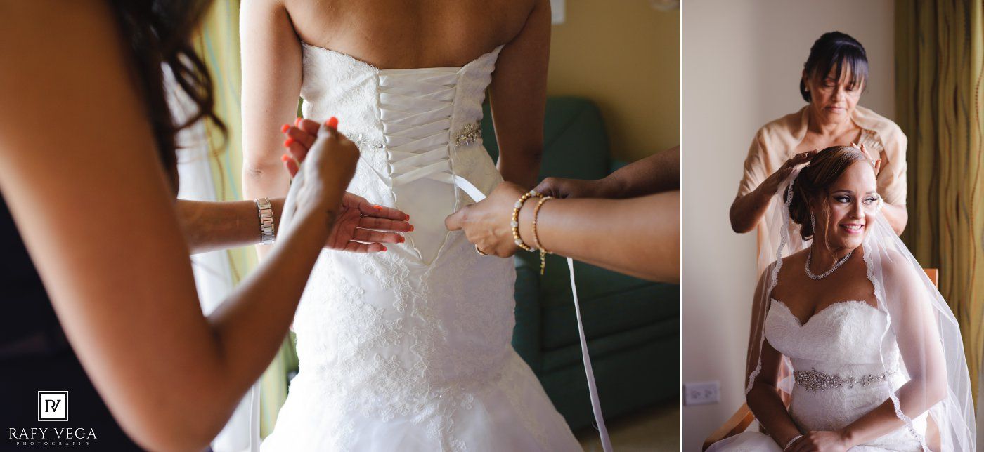 Bride getting her wedding dress laced up while another bride sits having her veil adjusted before the ceremony.