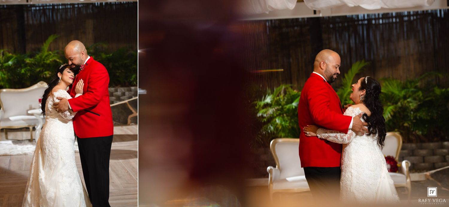 A couple shares their first dance, the groom in a red military uniform and the bride in a white lace gown, at an elegant venue.
