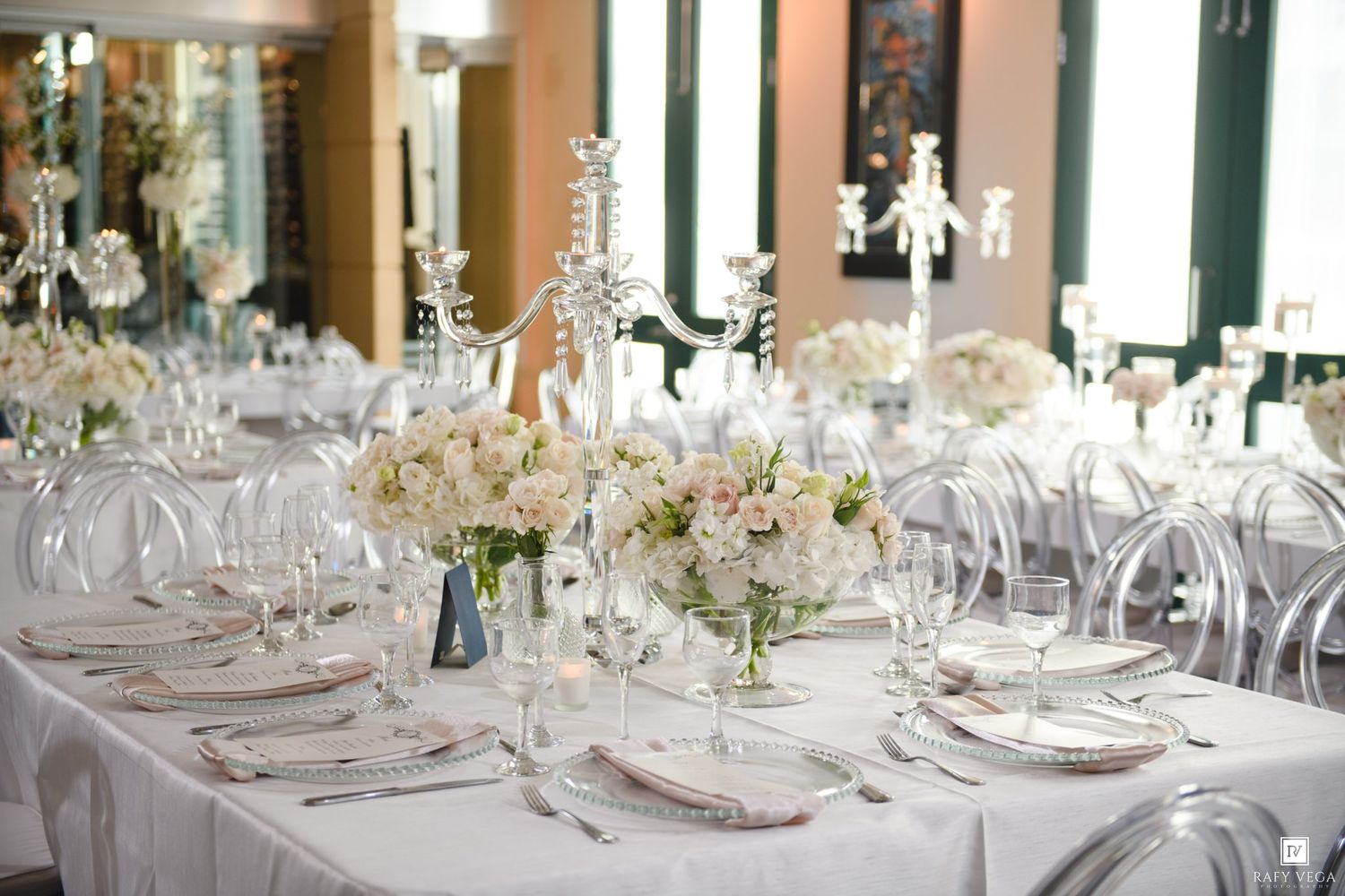 Elegant wedding reception with white tablecloths, crystal candelabras, and soft floral centerpieces in a bright, formal dining room.
