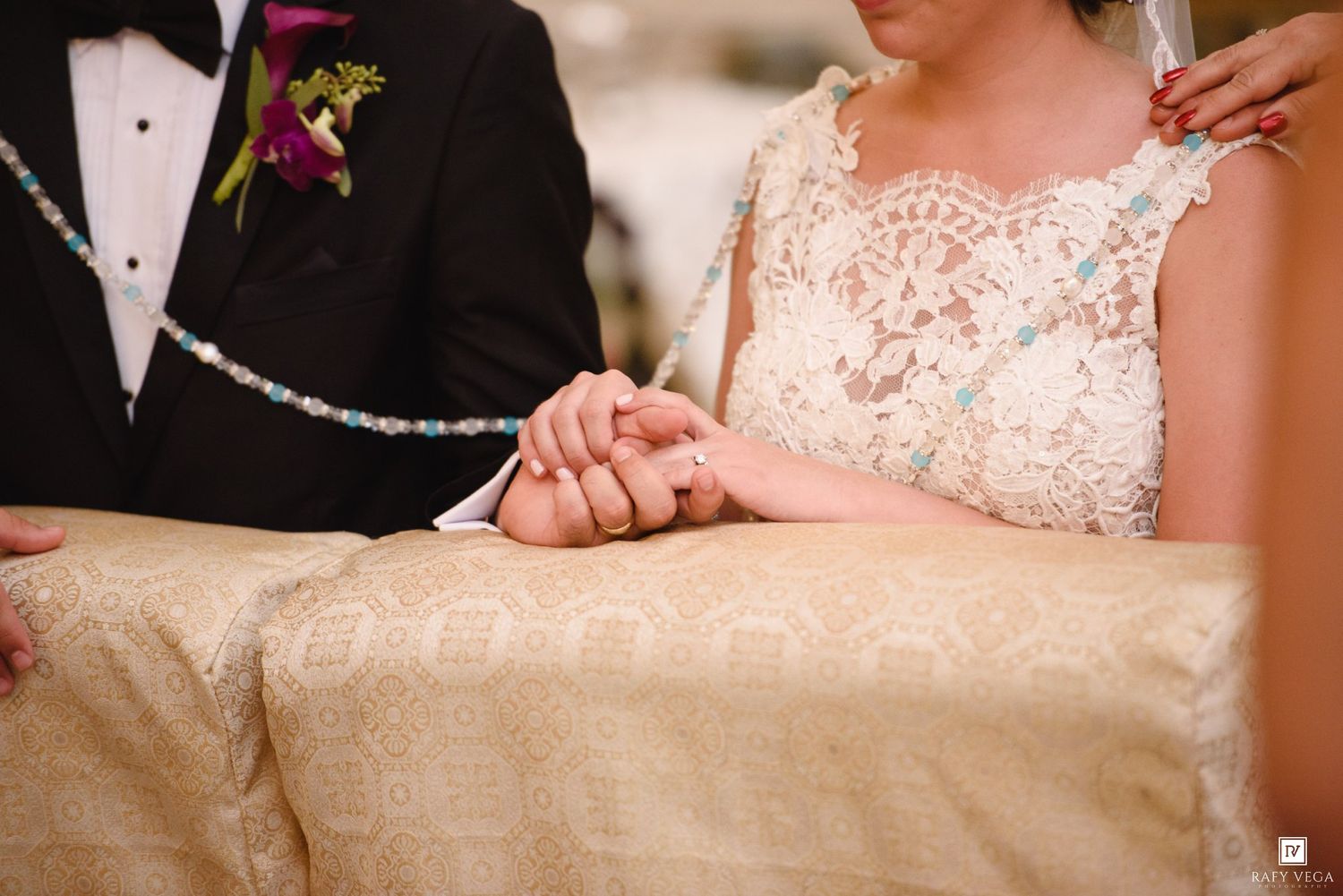 Bride and groom holding hands at wedding ceremony altar, bride wearing elegant lace dress.