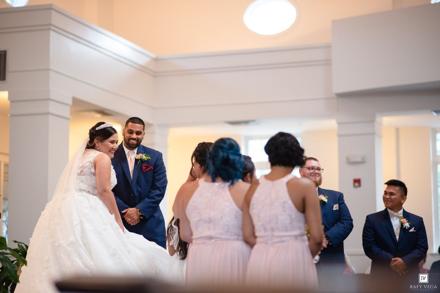 Bride and groom share a joyful moment during wedding ceremony with bridesmaids and groomsmen in elegant venue.