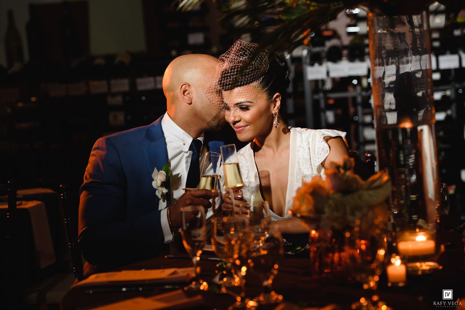 Bride and groom toast champagne at elegant candlelit wedding reception table, sharing a romantic moment.