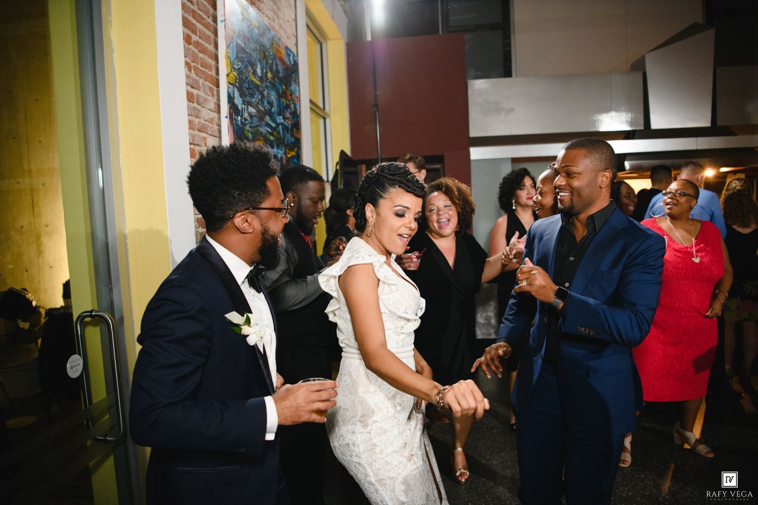 Bride and groom dancing joyfully at wedding reception surrounded by smiling guests in elegant venue.