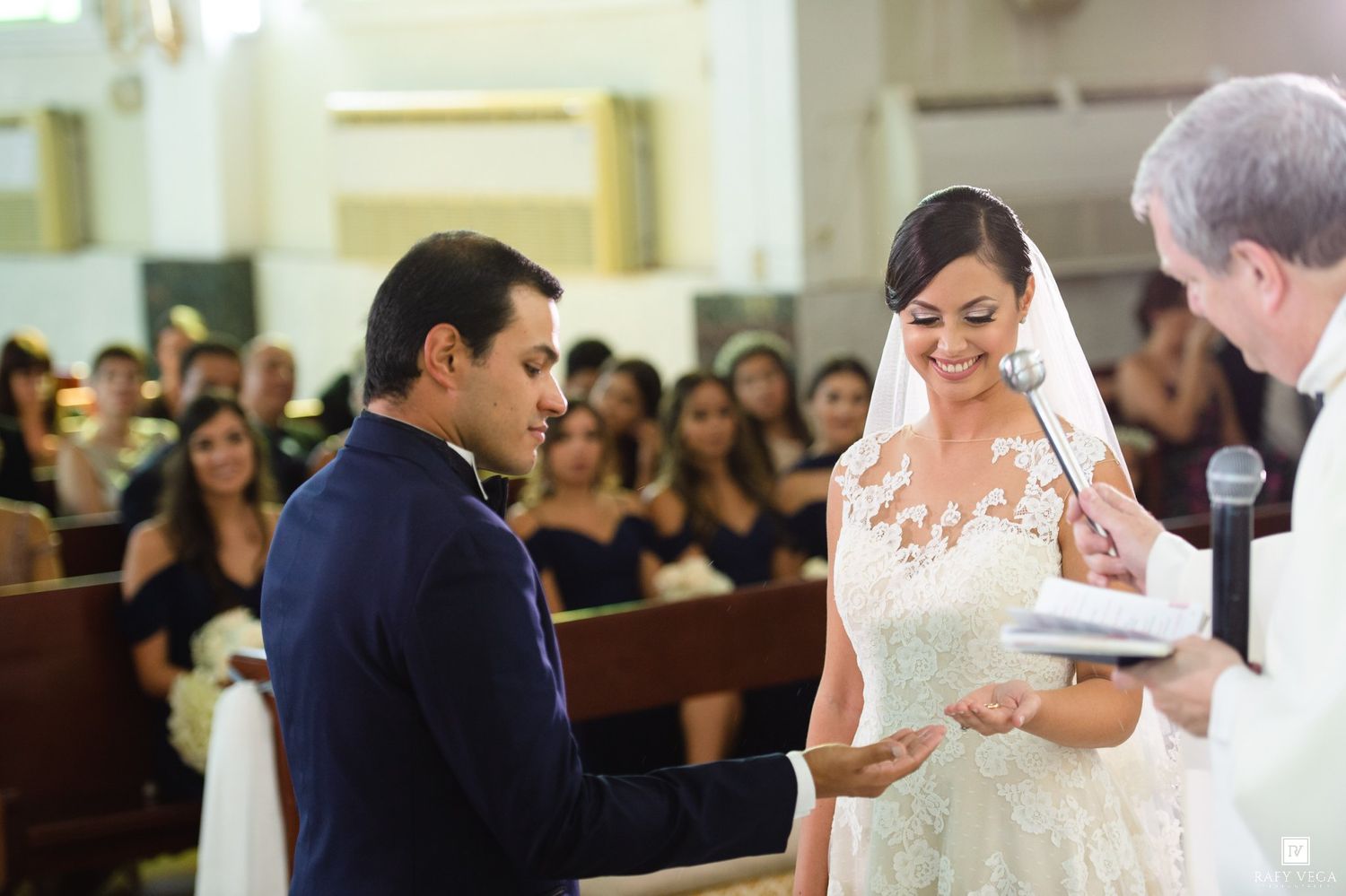 Bride and groom exchange vows at church altar during elegant wedding ceremony, bride wearing lace gown and veil.
