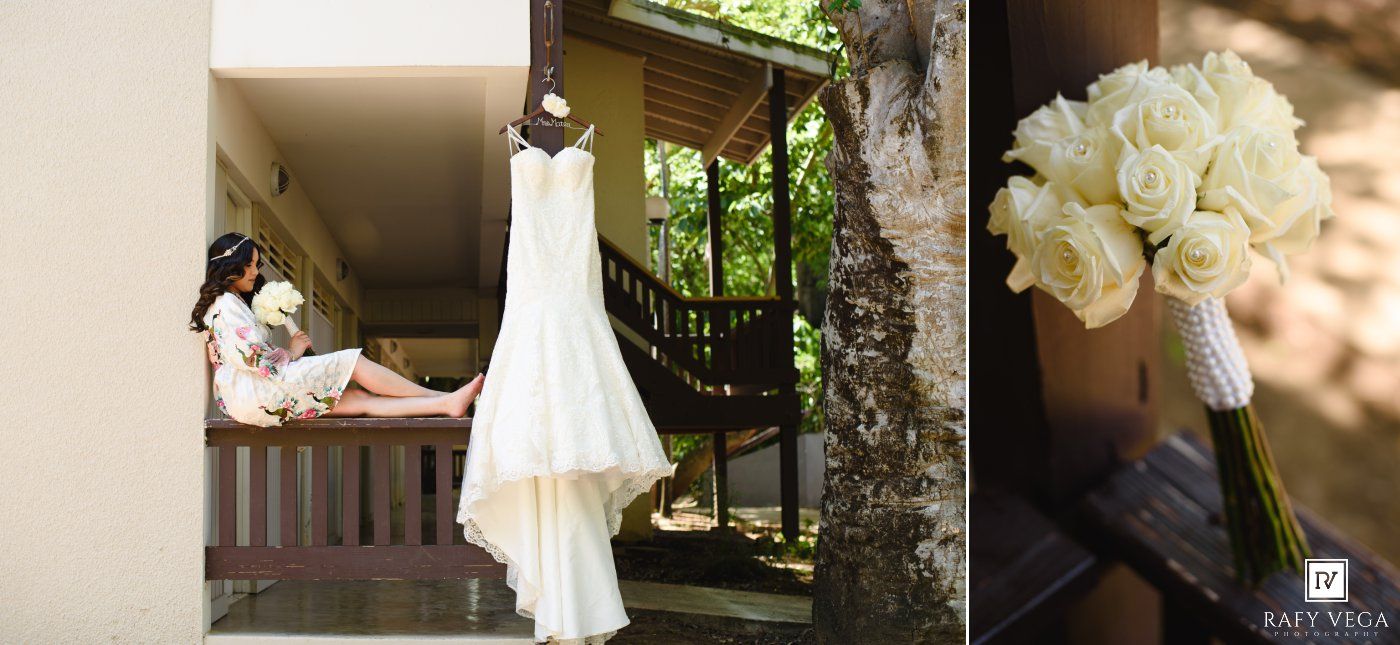 Bride in robe on balcony, elegant white wedding gown hanging, and a bouquet of white roses on wedding day.