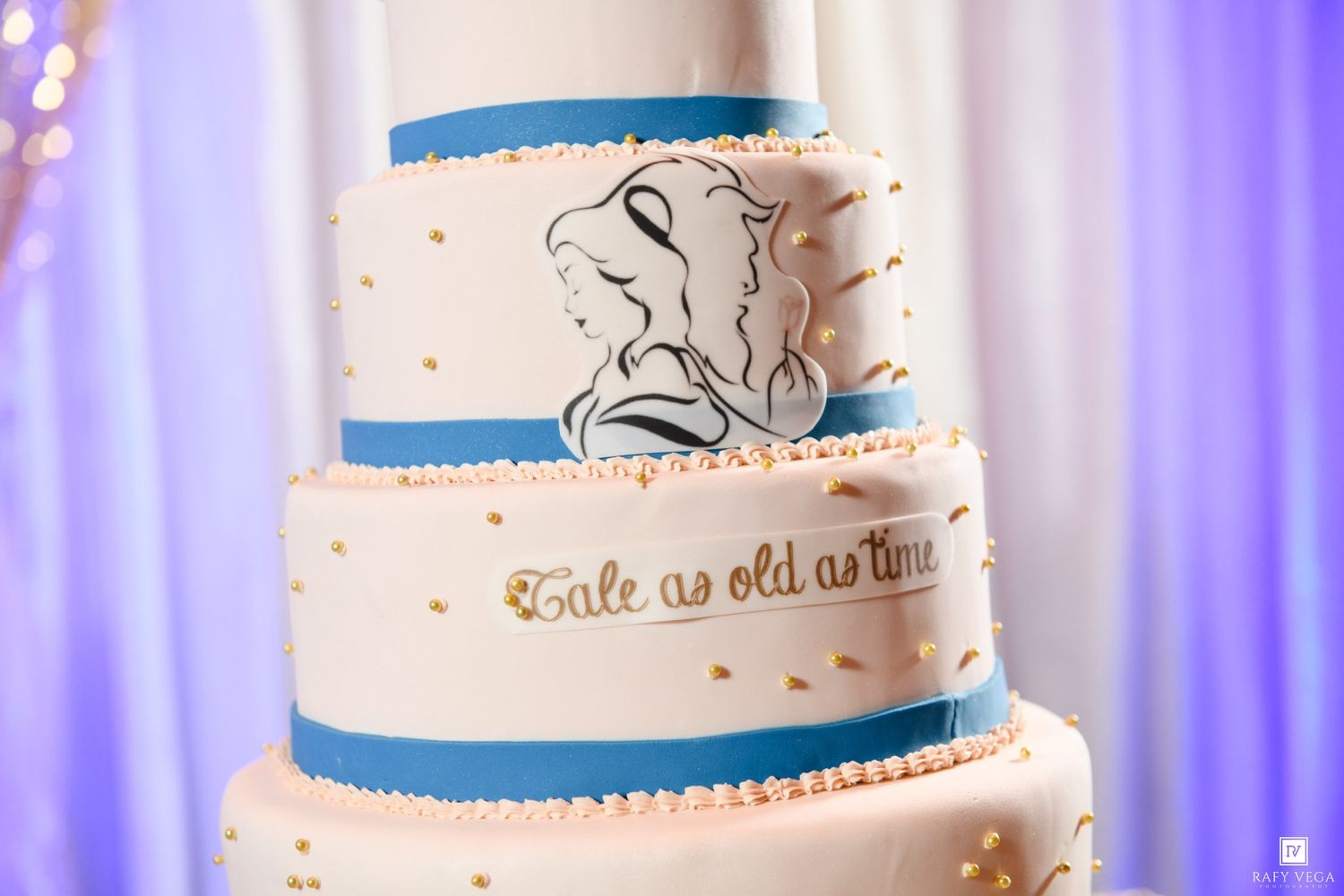 Beauty and the Beast wedding cake detail showing Tale as Old as Time inscription with blue fondant accents.