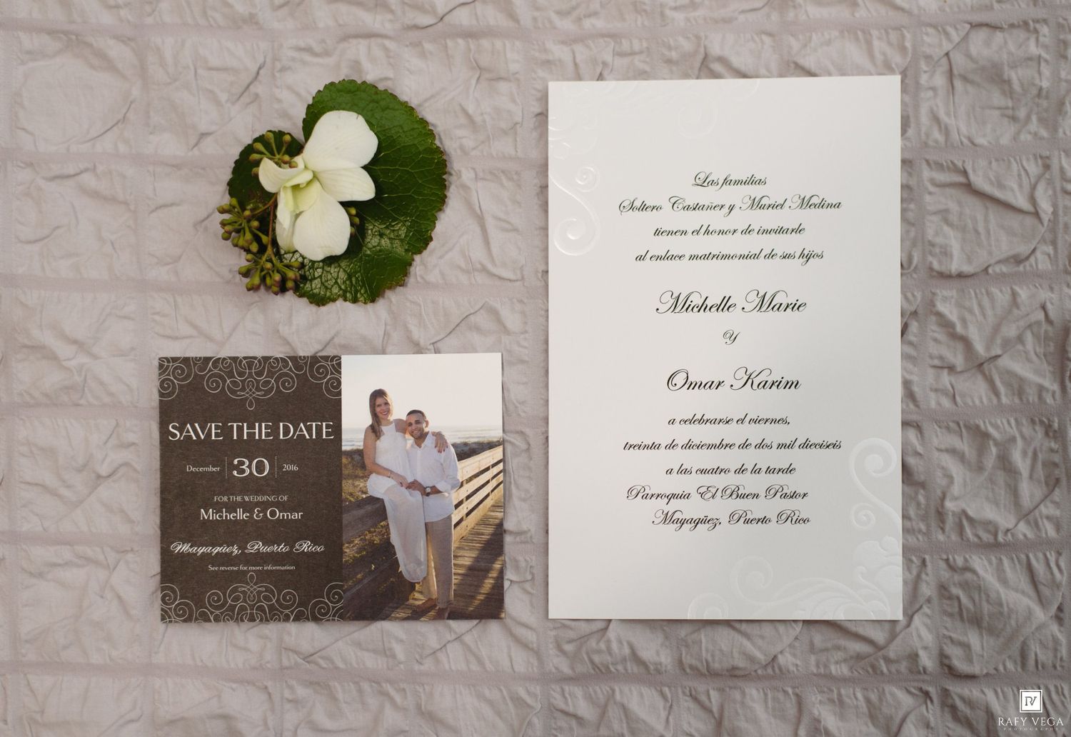 Elegant wedding stationery set with save the date card, formal invitation, and floral boutonniere on white background.