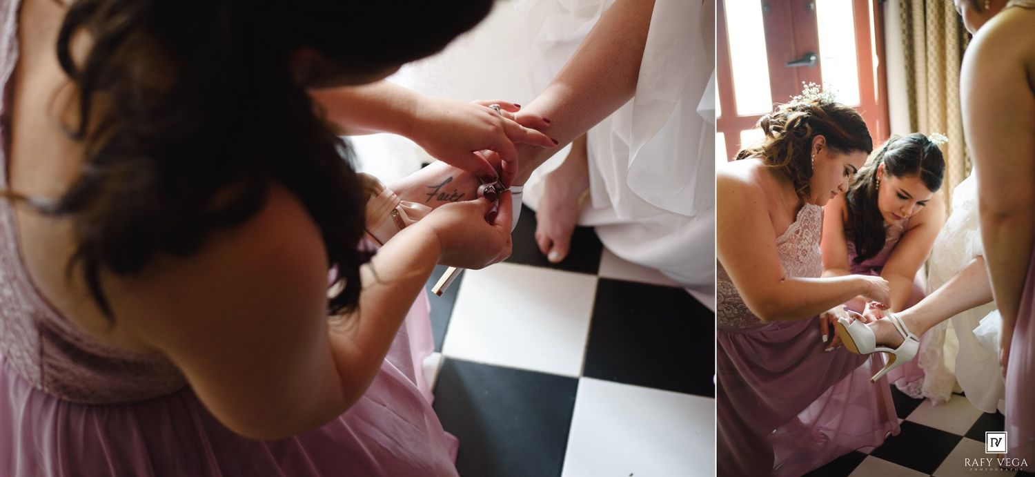 Bridesmaids in pink dresses helping bride with final wedding preparations.