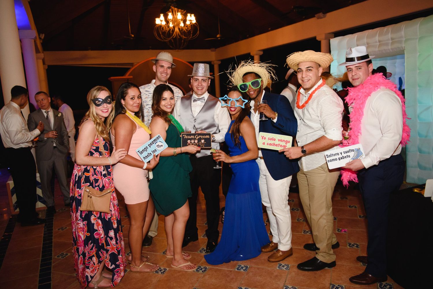 Group of friends posing in fun costumes and accessories at a festive wedding reception party.