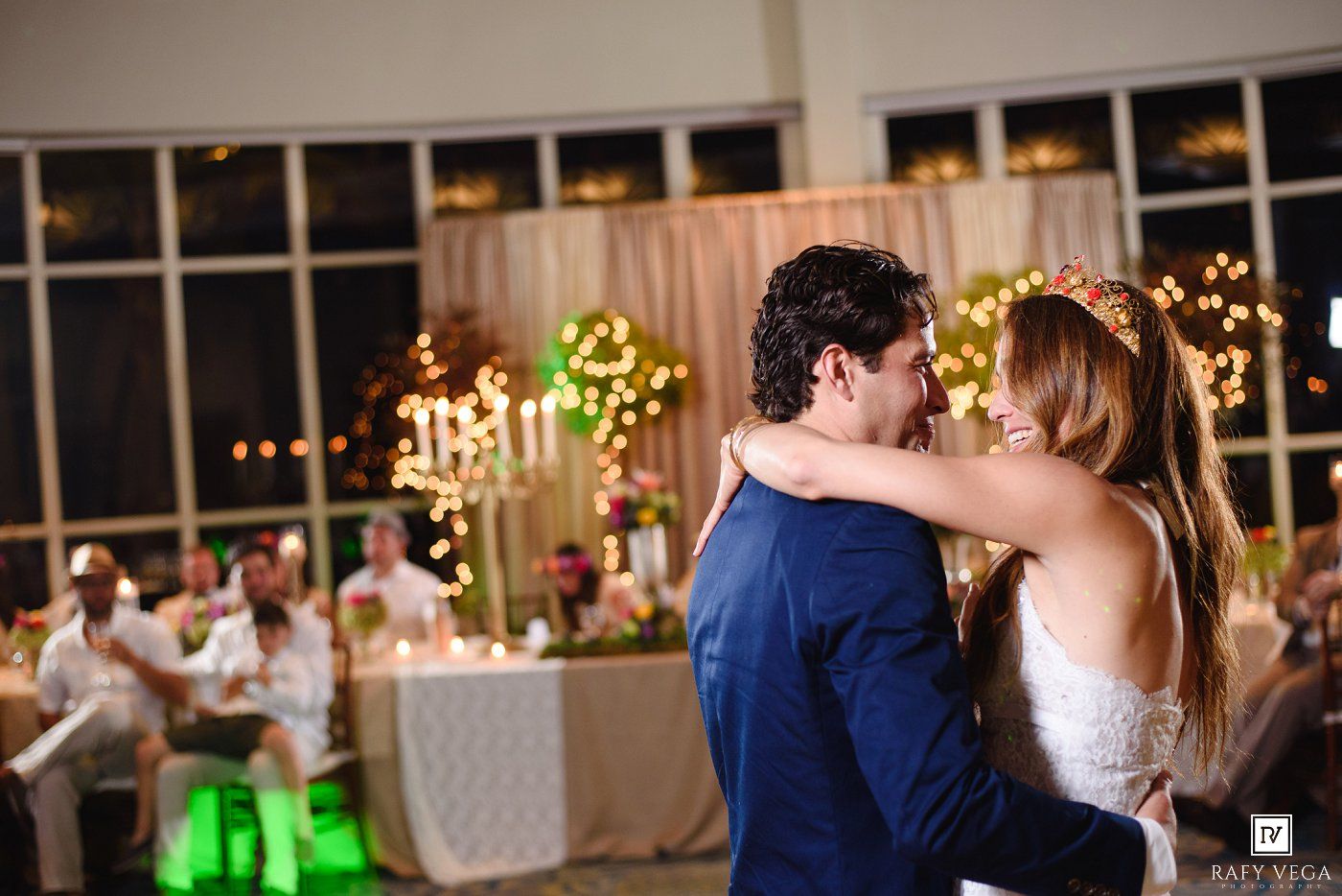 Bride and groom share their first dance at a romantic wedding reception with warm glowing lights in the background.