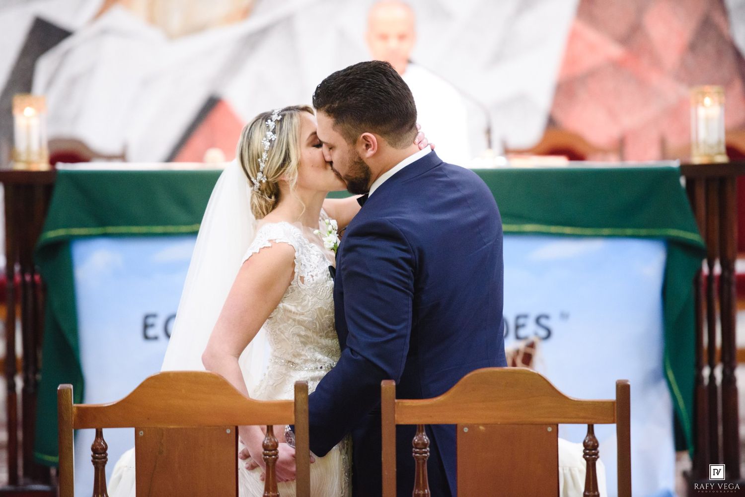 Bride and groom share their first kiss at the altar during a romantic church wedding ceremony.
