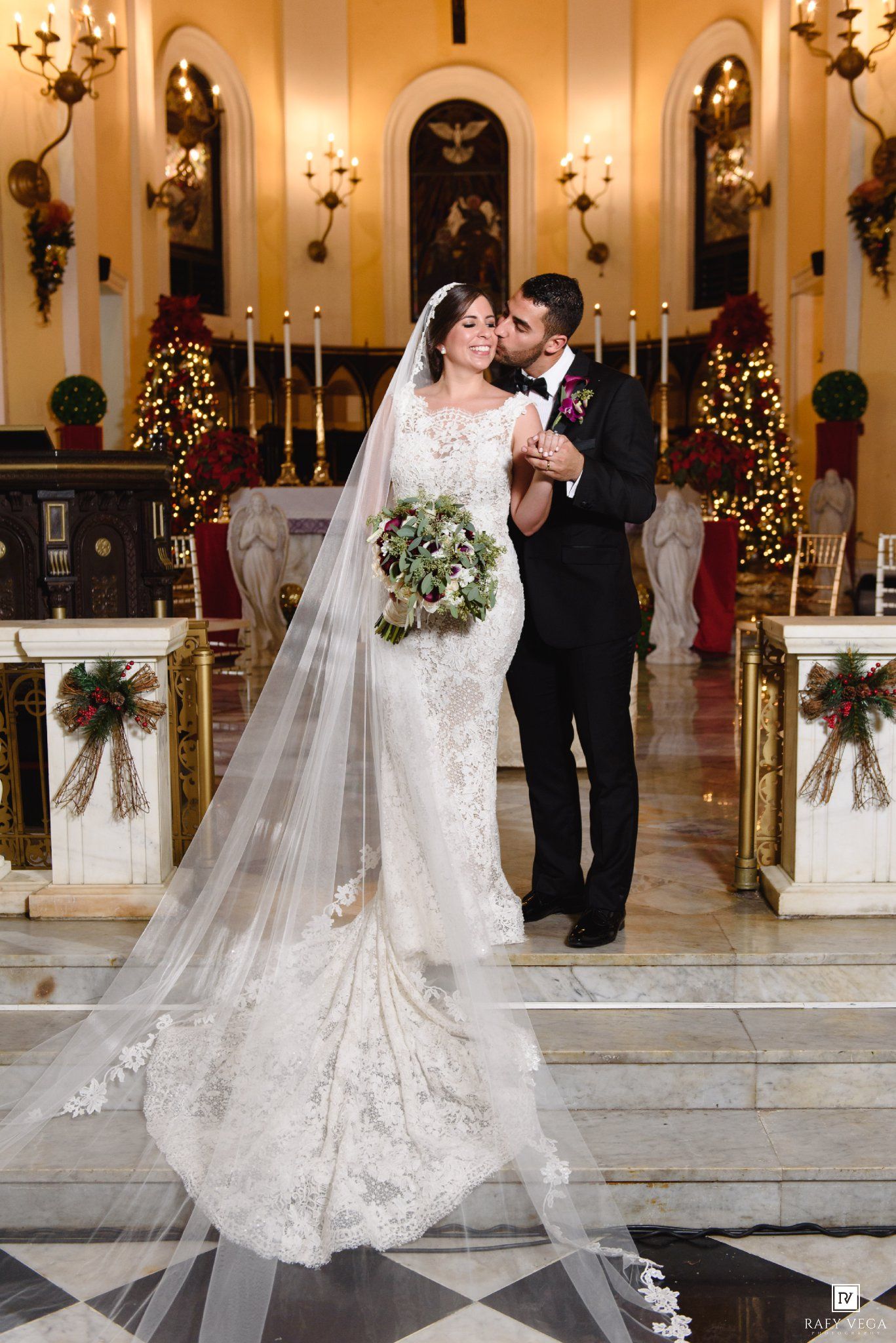 Bride and groom share a kiss at the altar of a decorated church during their wedding ceremony.