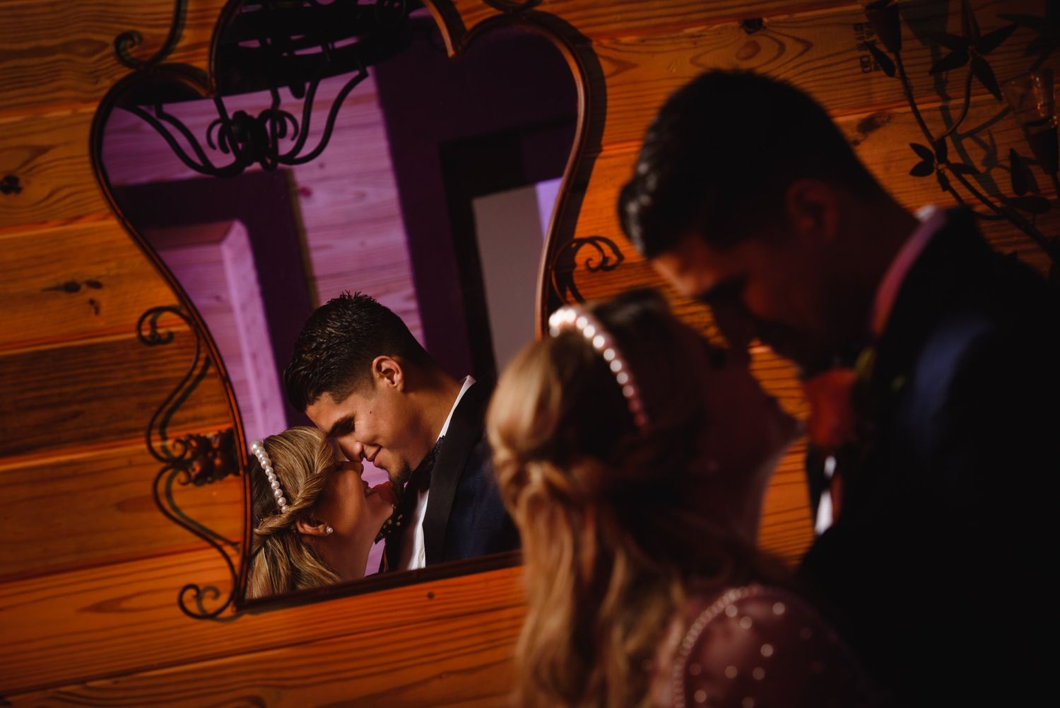 Couple sharing a romantic moment reflected in an ornate mirror at their wedding reception.
