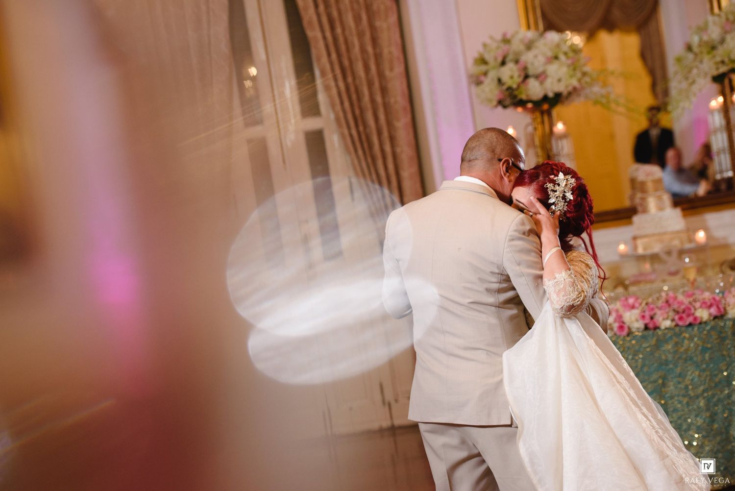 Bride and groom share a romantic first dance at elegant wedding reception with floral arrangements.