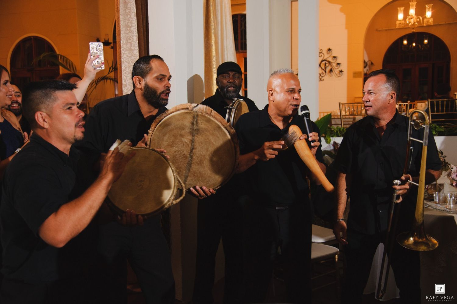 Live band performing at elegant event, musicians playing drums and trombone in black attire.