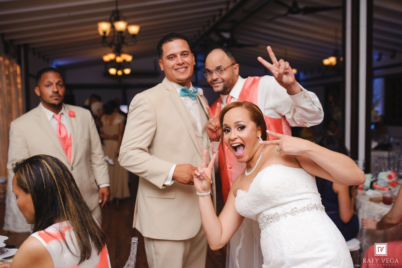 Bride and groom pose playfully with groomsmen at elegant wedding reception venue.