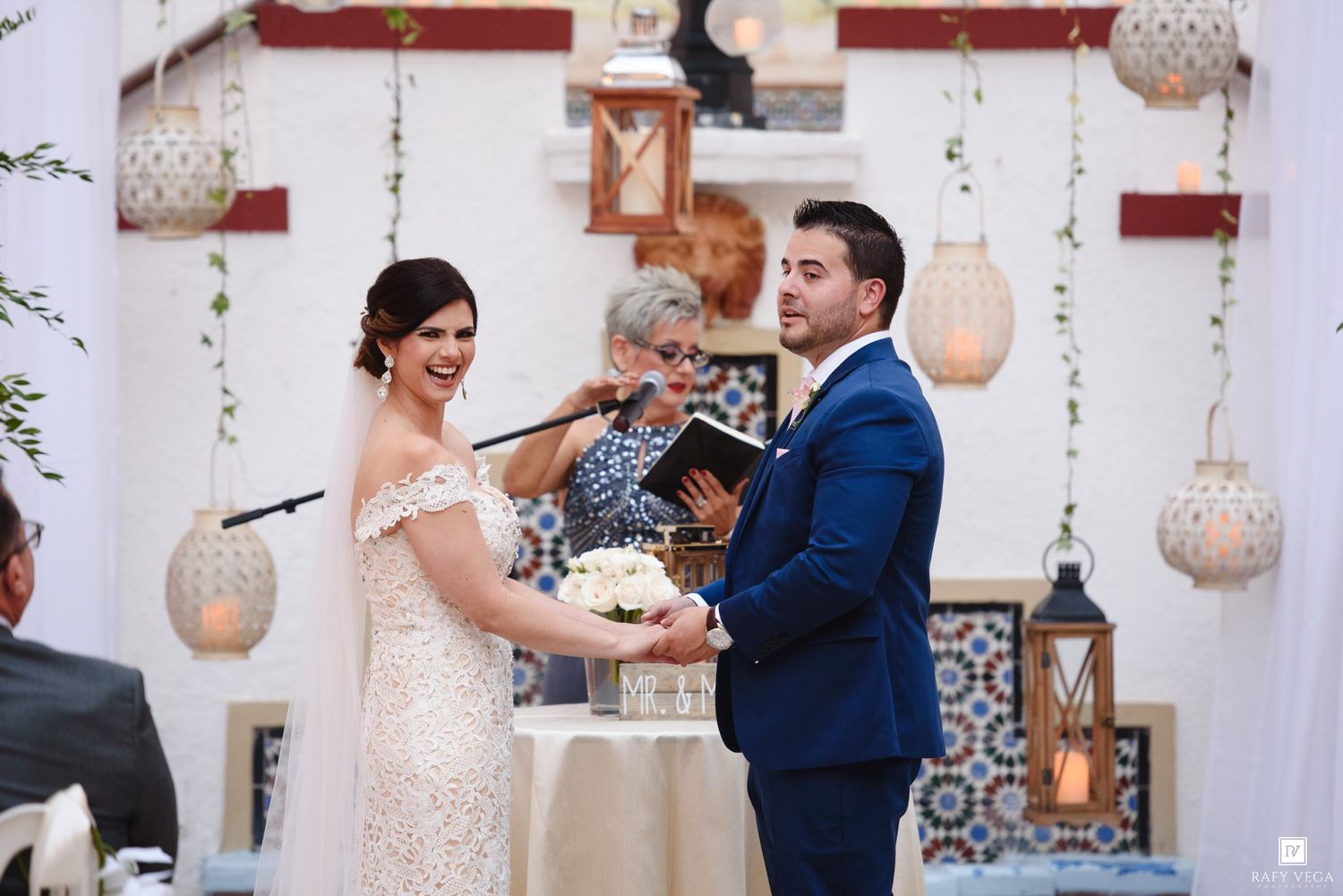 Bride and groom exchange vows at altar with officiant, surrounded by lanterns and Moroccan-inspired decor.