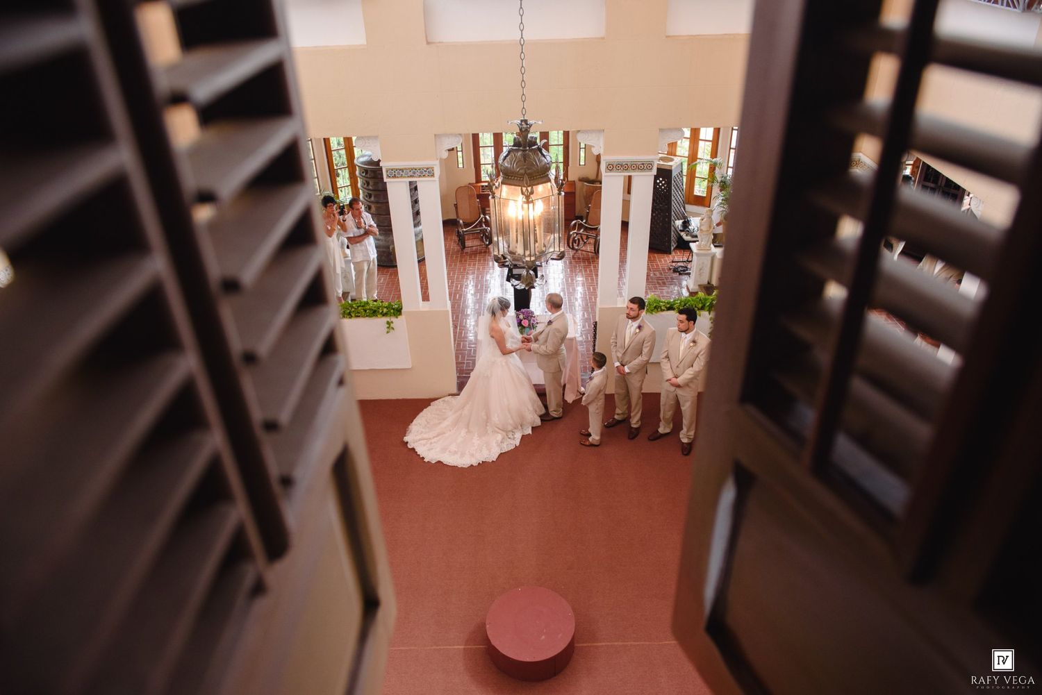 Aerial overhead view of bride and groom exchanging vows at elegant indoor wedding ceremony.