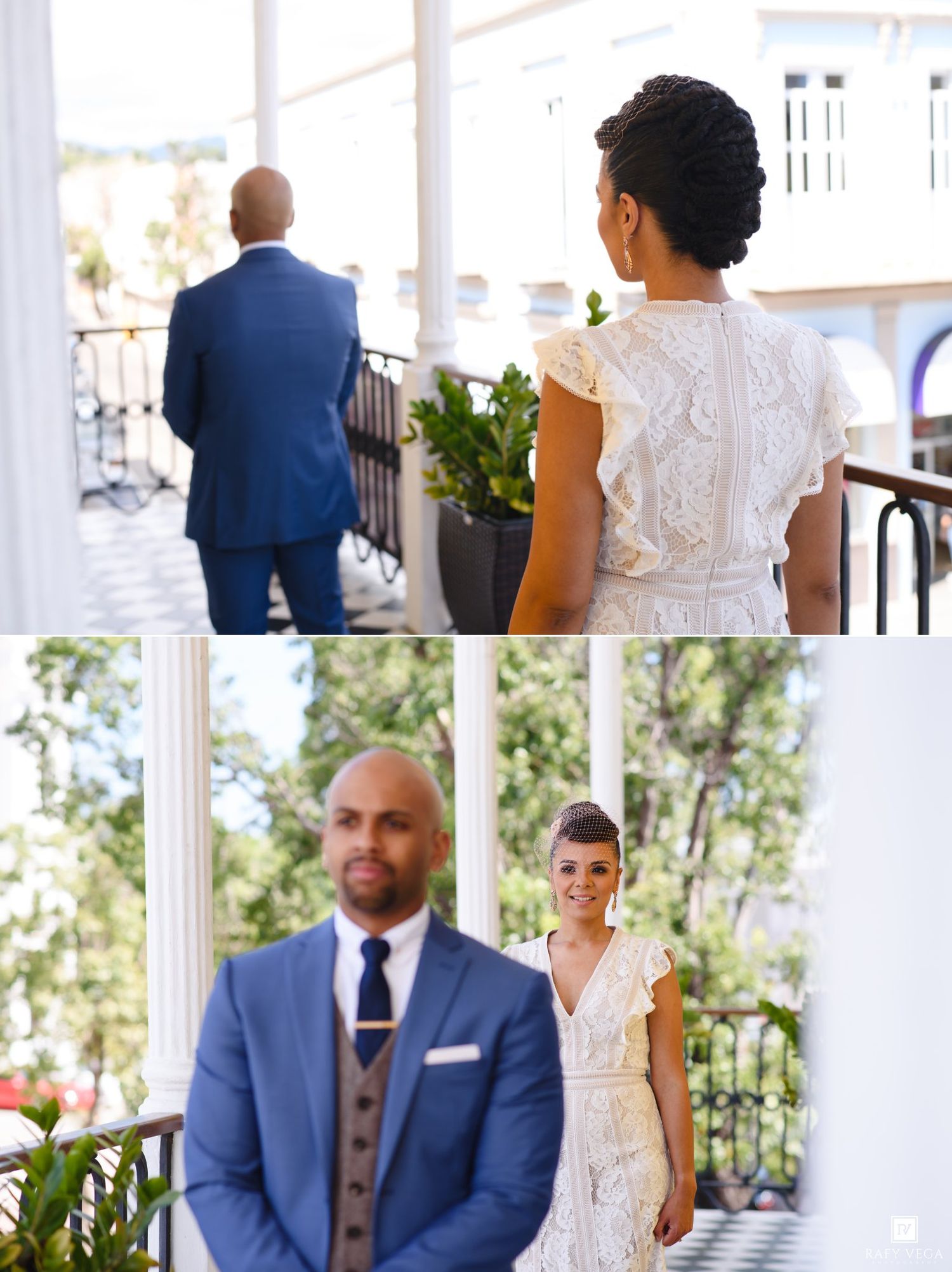 Bride in lace dress and groom in blue suit share a romantic first look moment on an elegant outdoor venue balcony.