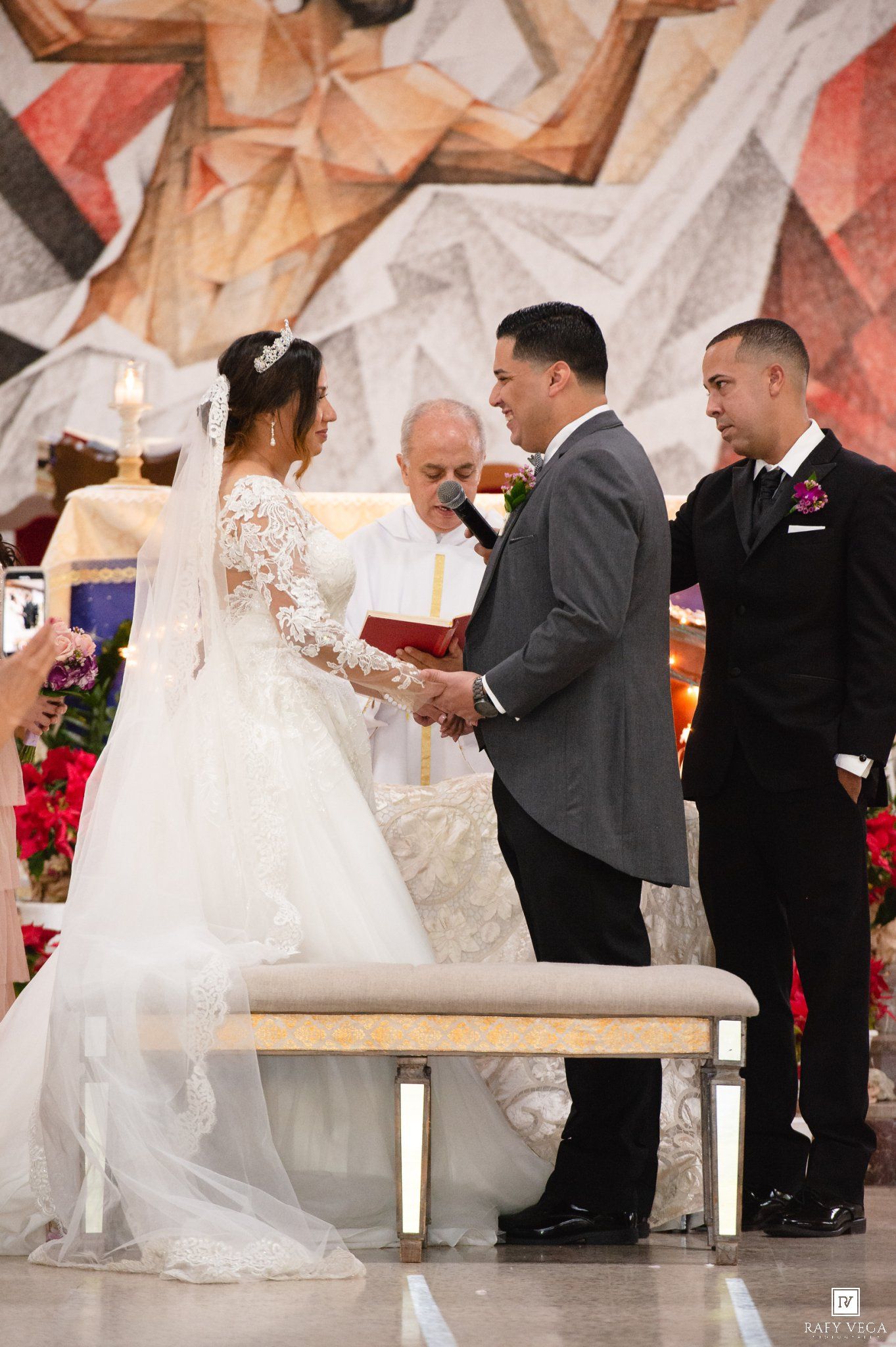 Bride and groom exchange vows at elegant church wedding ceremony with officiant and groomsman standing nearby.