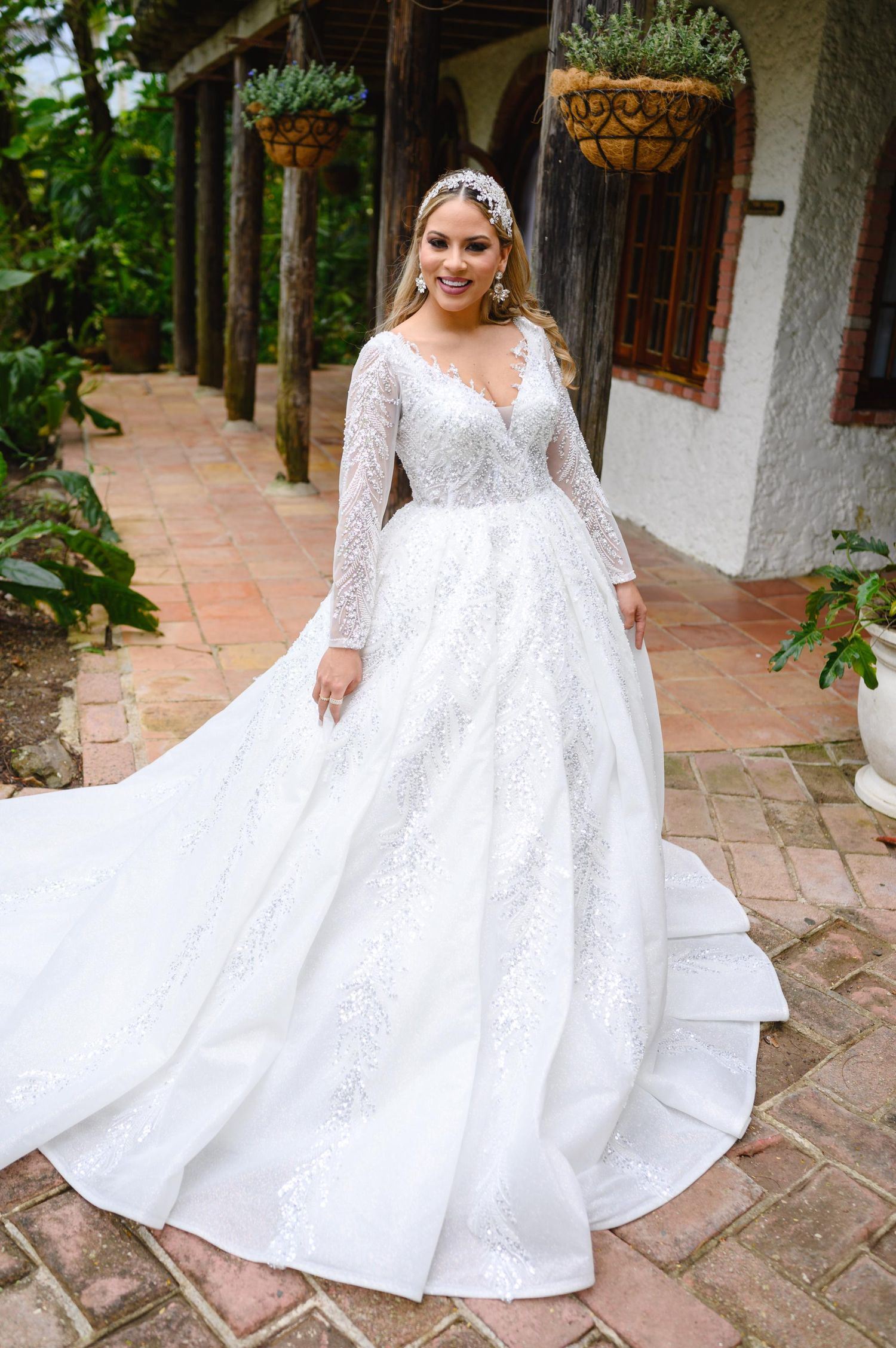 Plus-size bride wearing a long-sleeve lace ball gown wedding dress with V-neckline and cathedral train.