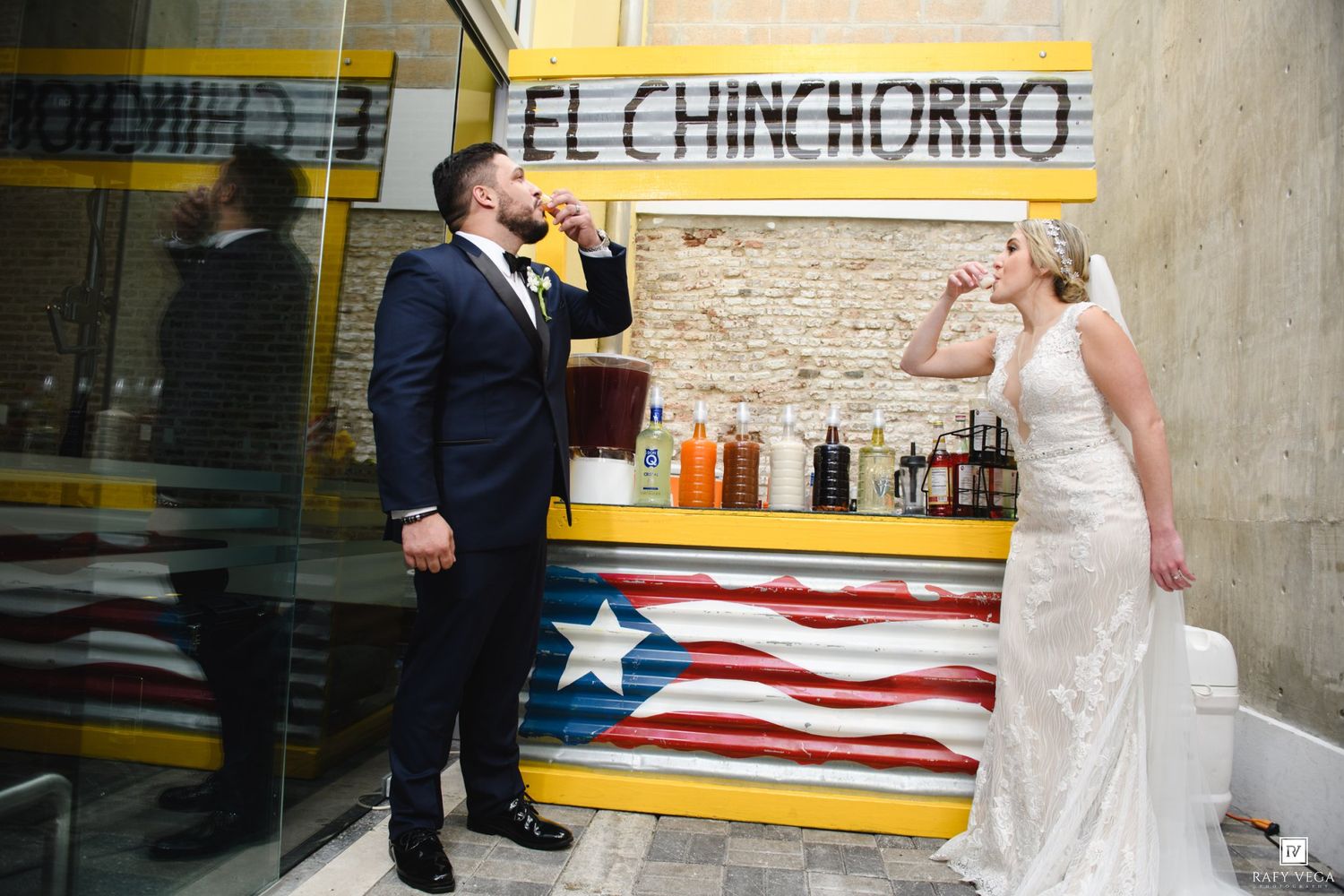 Bride and groom taking shots at El Chinchorro bar with Puerto Rican flag decor on their wedding day.