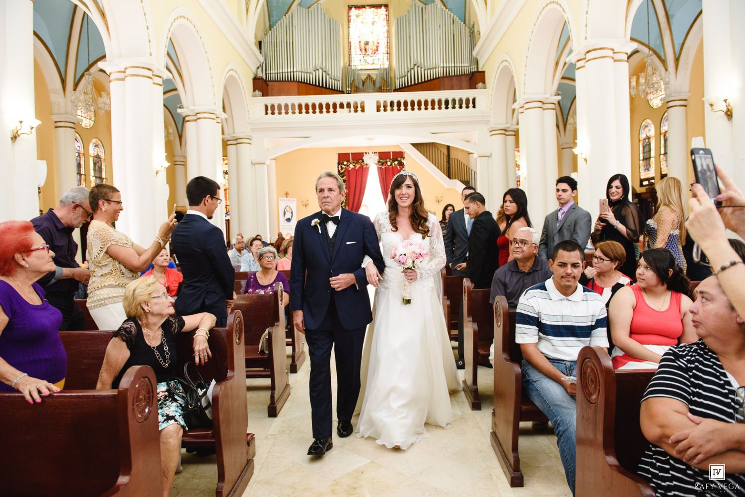 Bride and groom walking down the aisle in a beautiful church surrounded by wedding guests during ceremony.