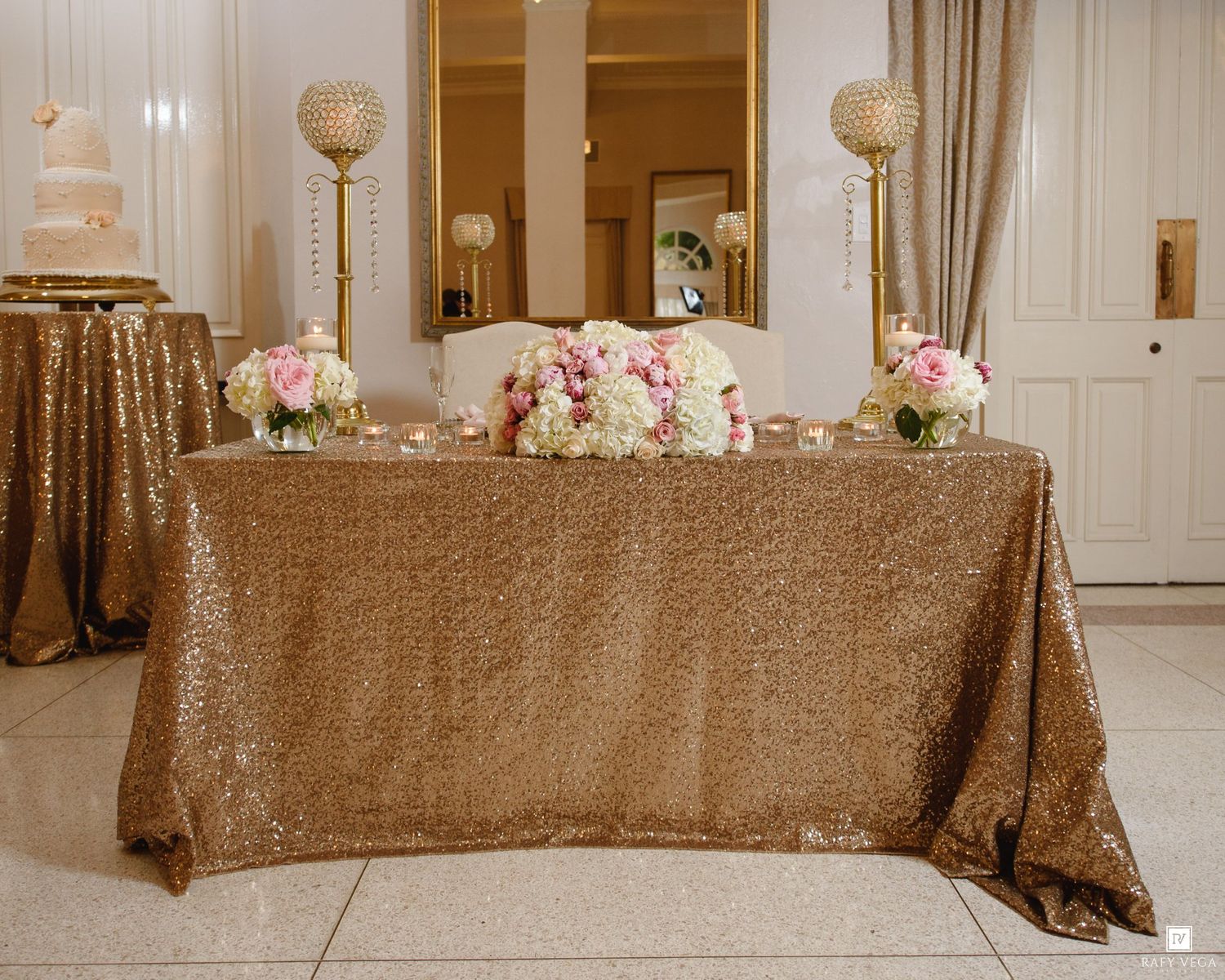 Elegant wedding sweetheart table with gold sequin tablecloth, crystal candelabras, and pink floral centerpieces.