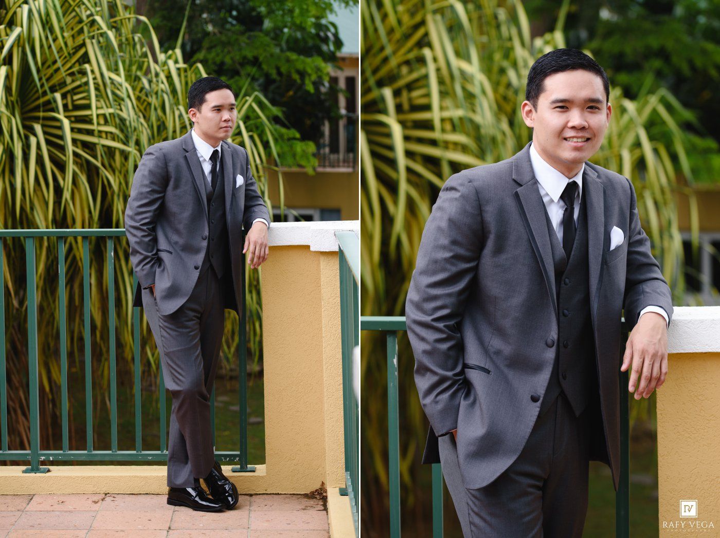 Young man in gray suit with white pocket square poses outdoors near green railing and tropical plants.