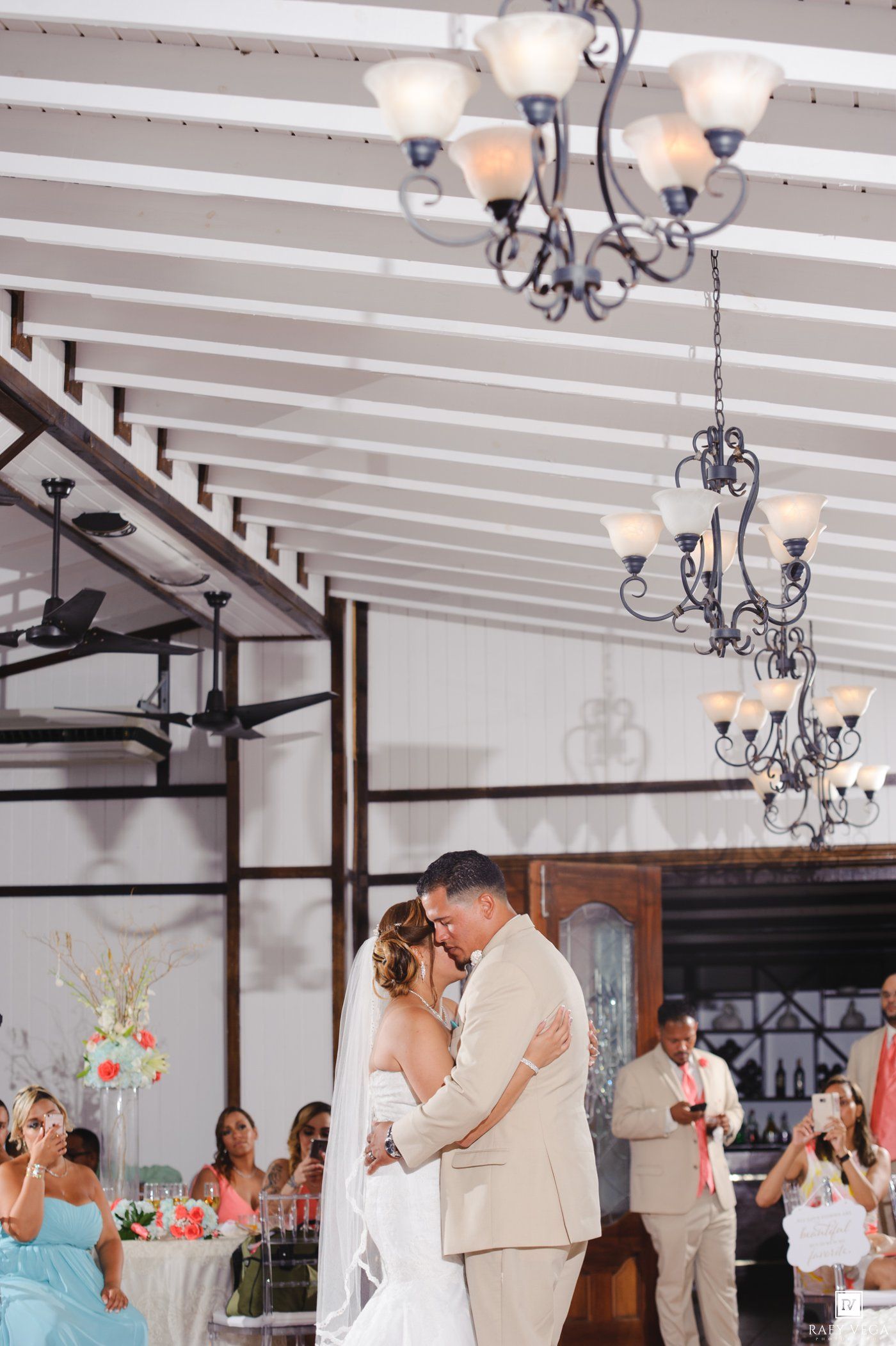 Bride and groom share their first dance under elegant chandeliers at a romantic wedding reception.