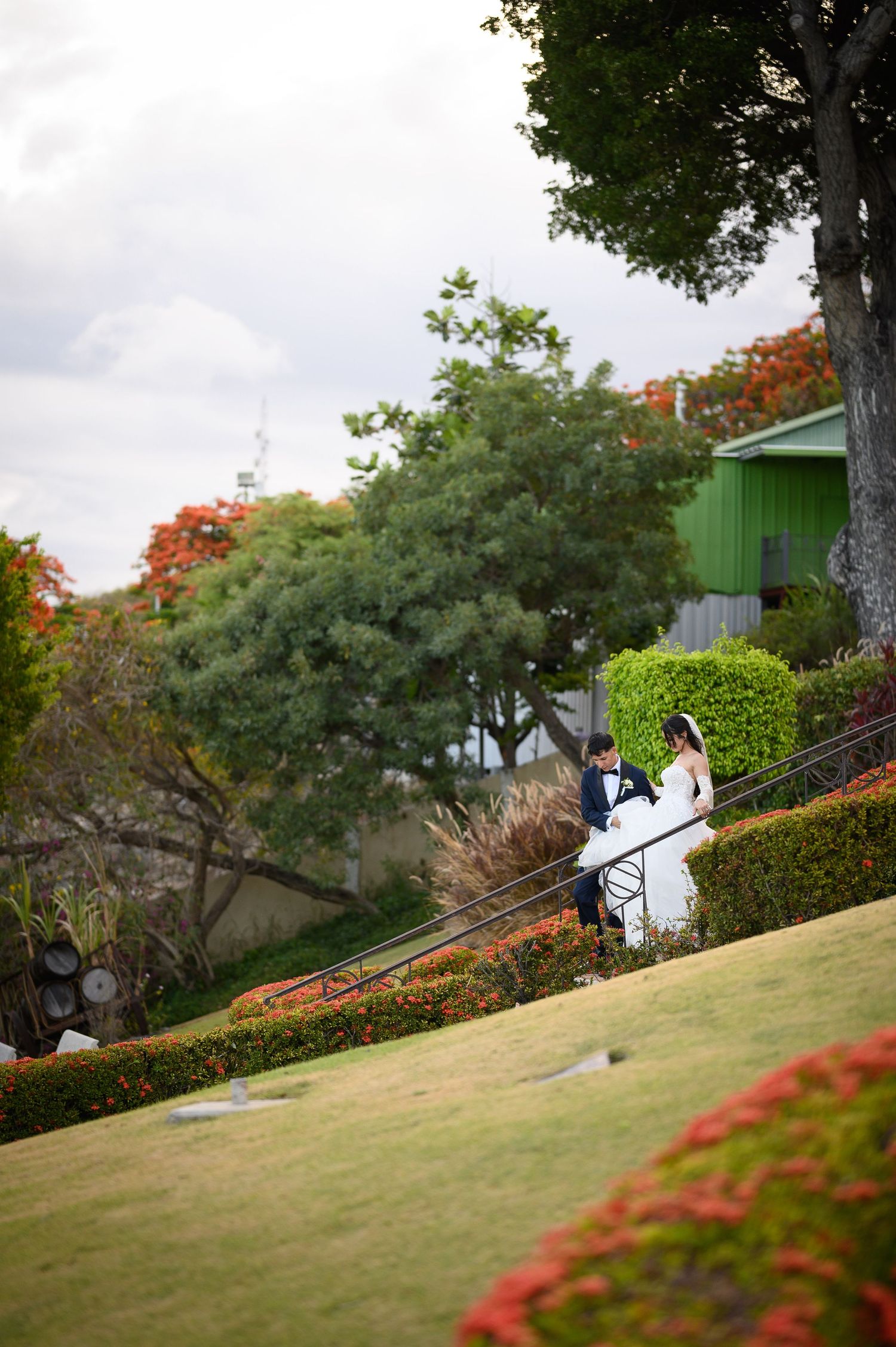 A bride and groom walk hand in hand down a lush garden path on their wedding day.
