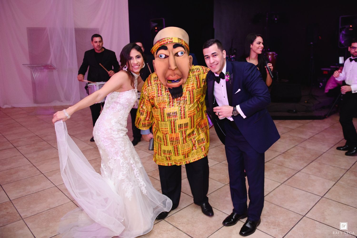 Bride and groom posing with a costumed character at their wedding reception on the dance floor.