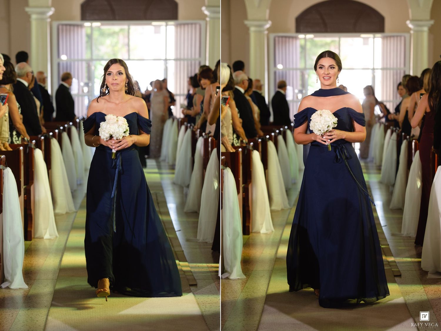Bridesmaid in navy blue off-shoulder gown walking down a wedding aisle holding white bouquet.