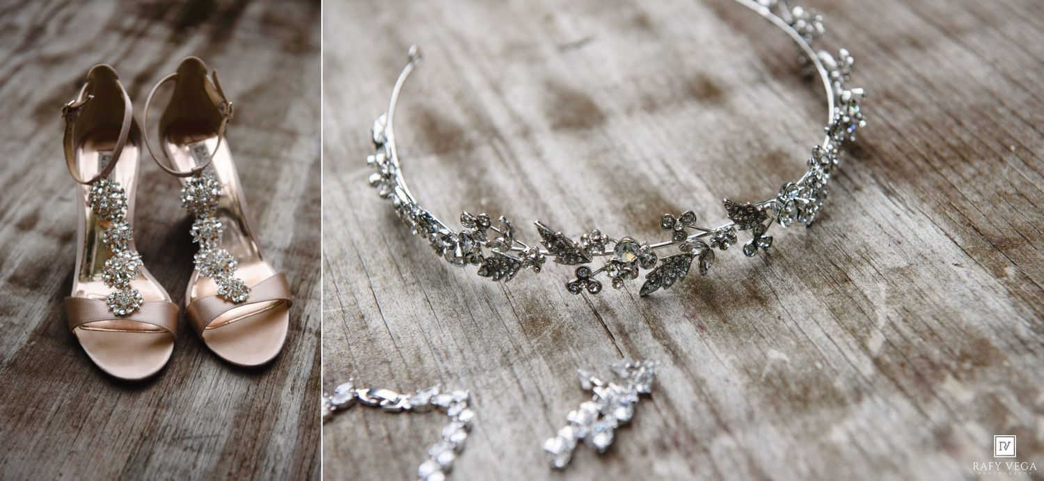 Elegant bridal accessories including blush pink heels, crystal hair vine, and delicate diamond earrings on rustic wood.