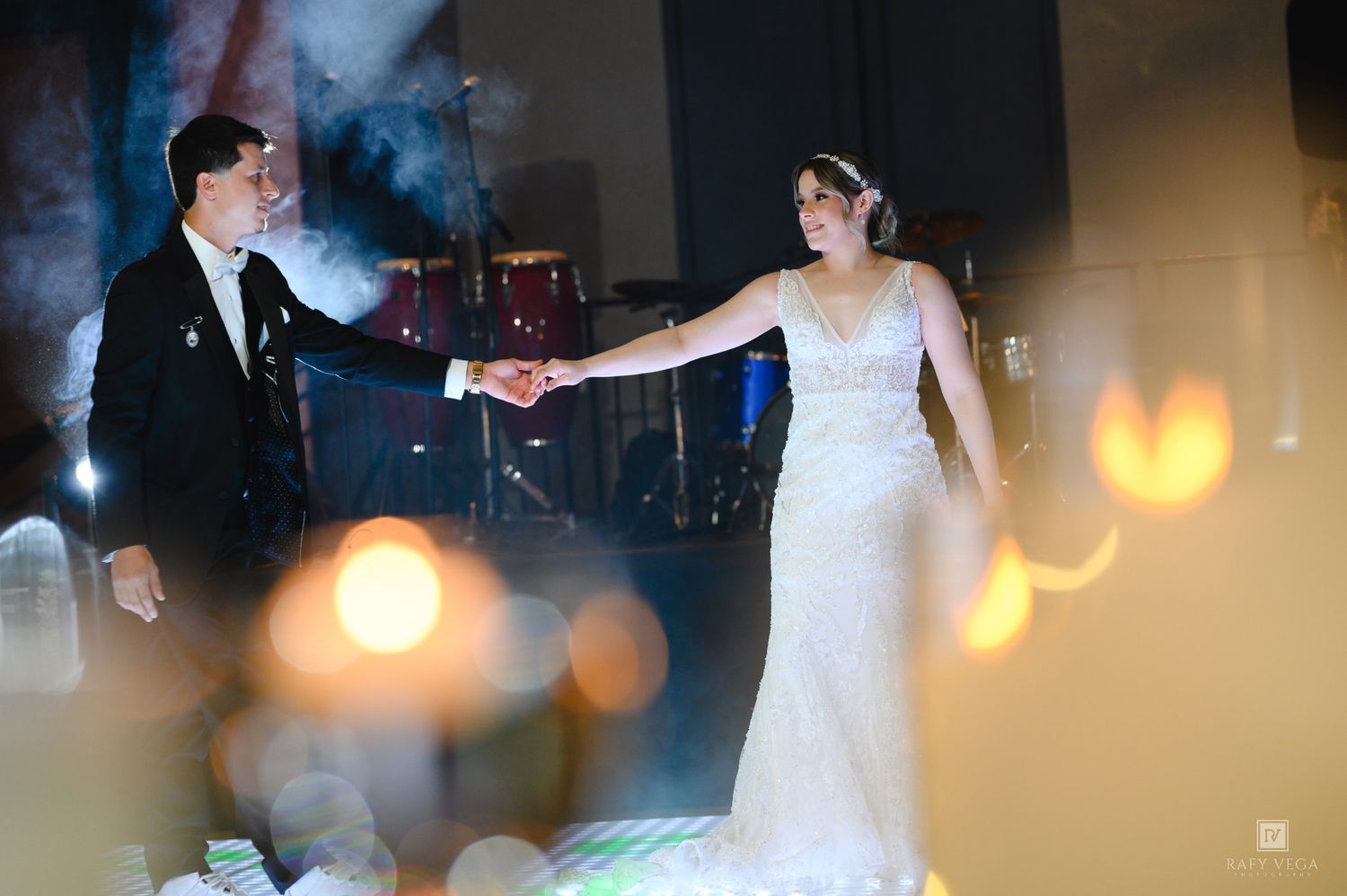 Bride and groom hold hands on the dance floor during their elegant wedding reception with candlelight.