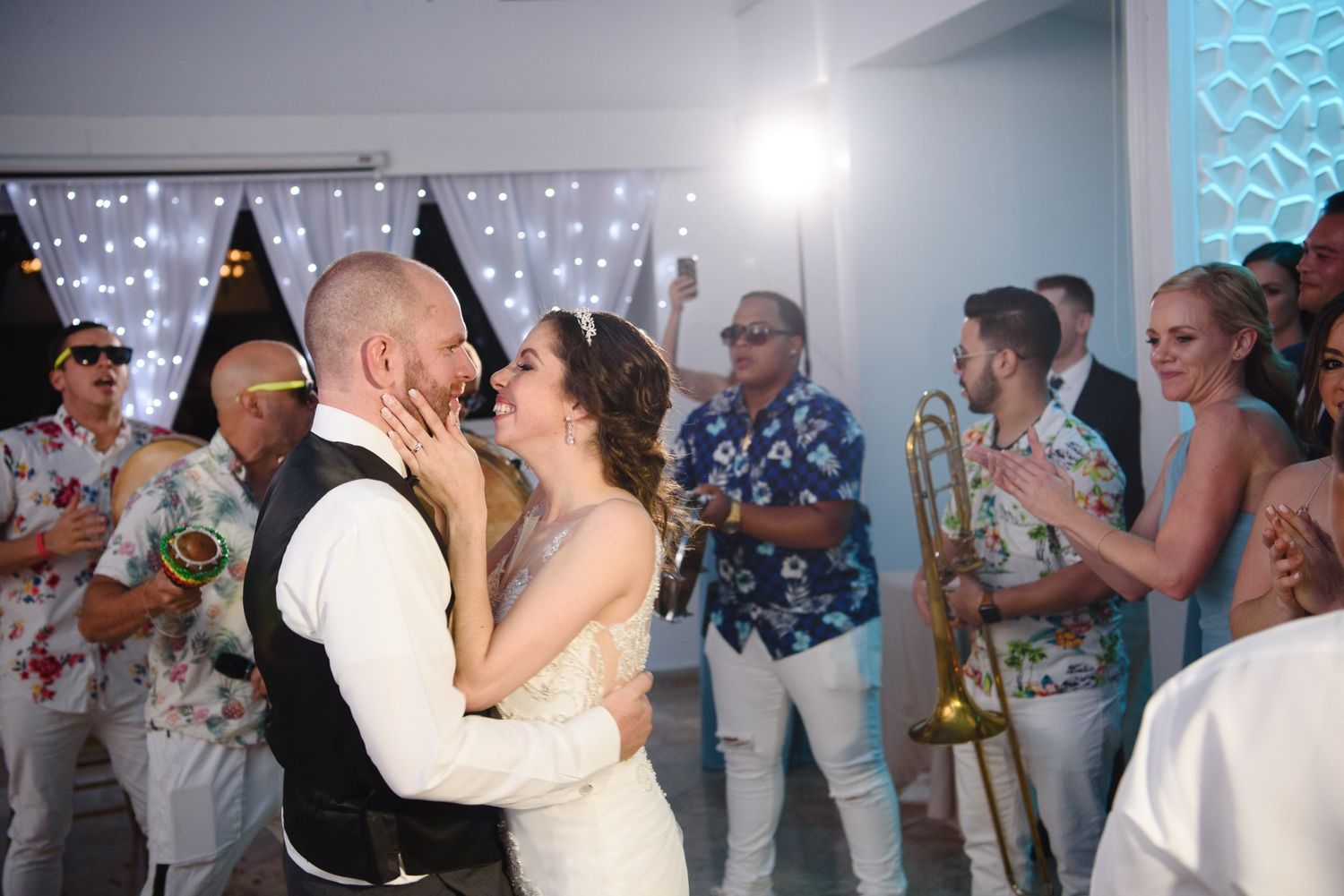 Bride and groom share first dance at outdoor wedding reception with guests and band performing in background.