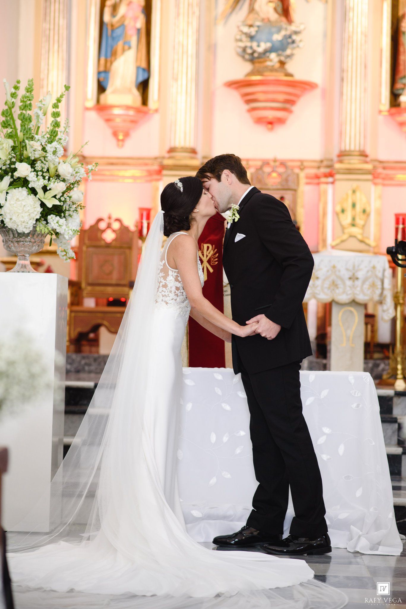 Bride and groom share their first kiss at the altar during a romantic church wedding ceremony.