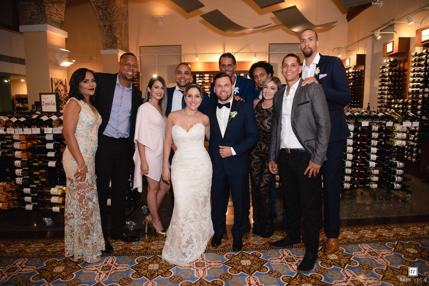 Wedding couple poses with family and friends in a wine cellar restaurant during their reception celebration.