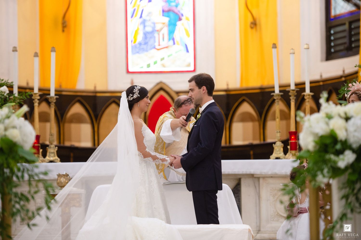 A bride and groom exchange vows at a decorated church altar during their elegant wedding ceremony.