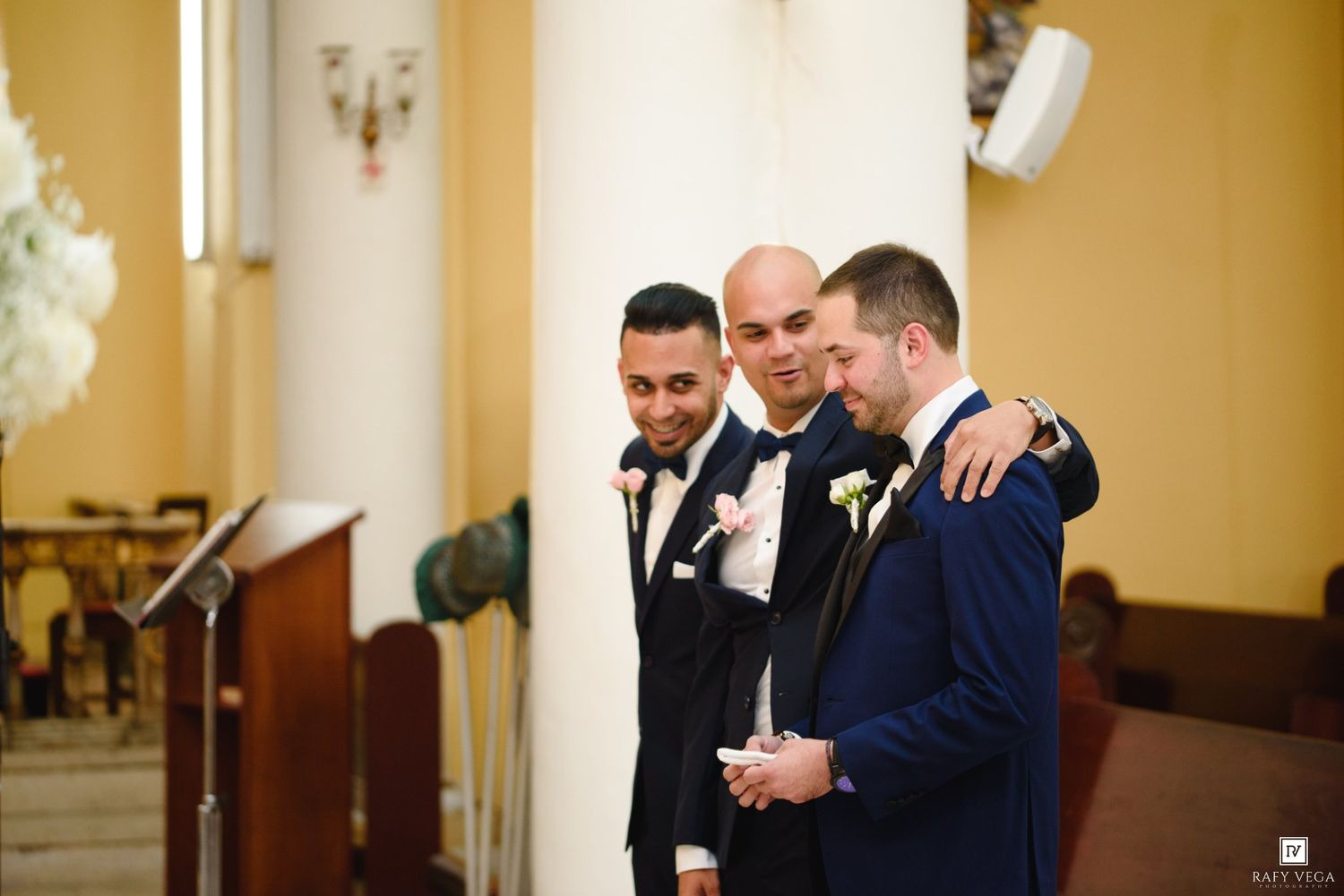 Groomsmen sharing an emotional moment together inside a church before the wedding ceremony begins.