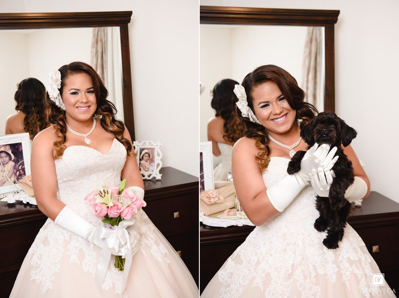 Bride in white strapless gown holding pink bouquet and black puppy, smiling in front of mirror.