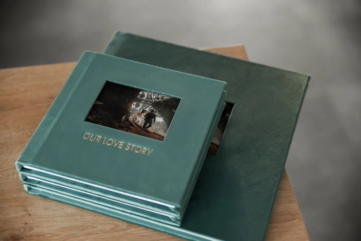 Stack of teal green wedding photo albums with 