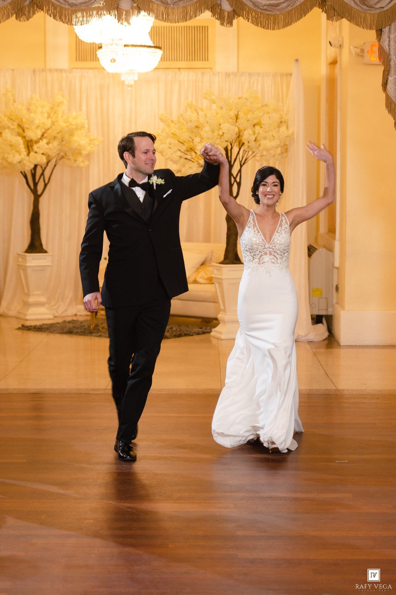 Bride and groom share first dance at elegant wedding reception, bride in white gown, groom in black tuxedo.