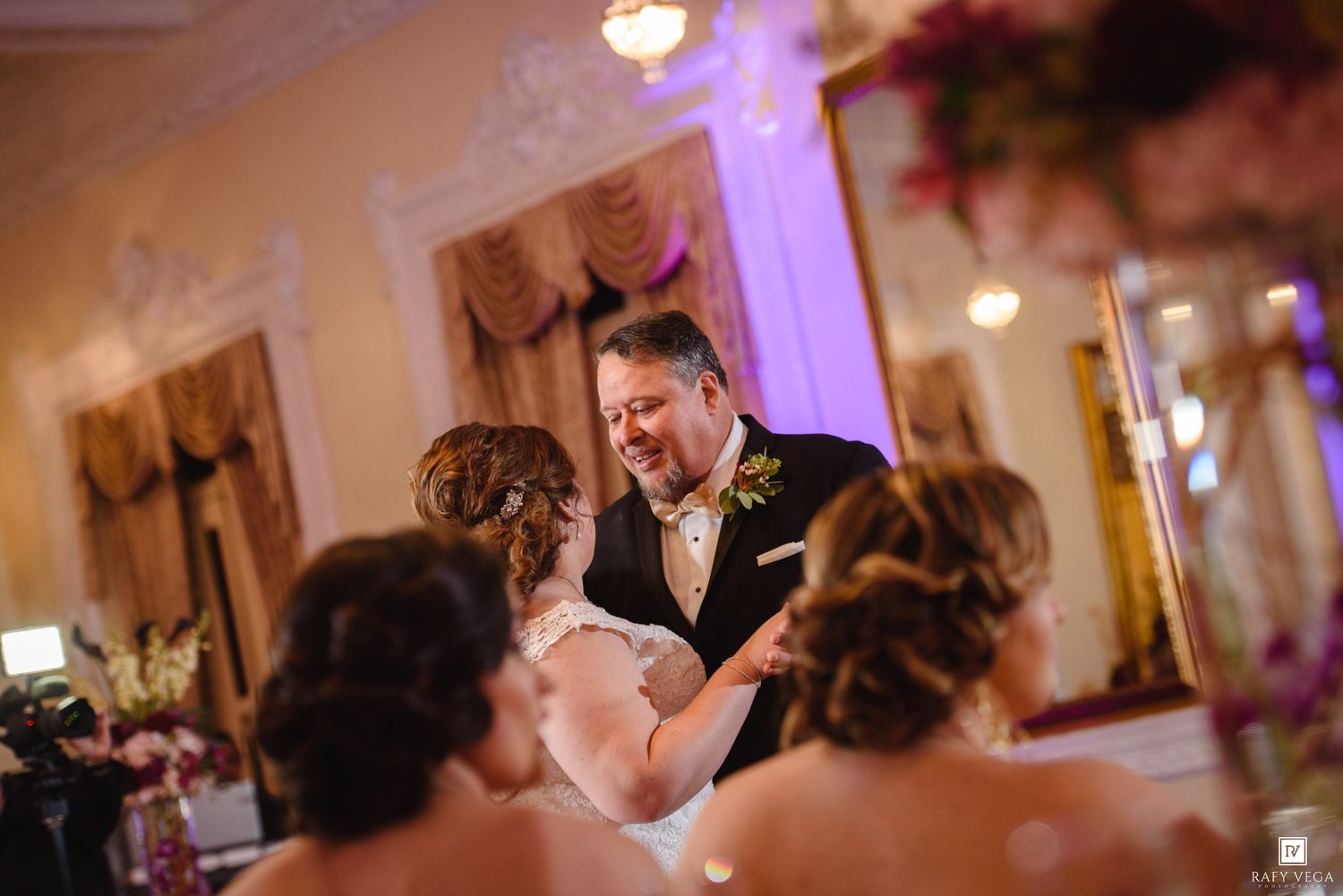 Bride and groom share their first dance at an elegant wedding reception with warm lighting and floral decorations.
