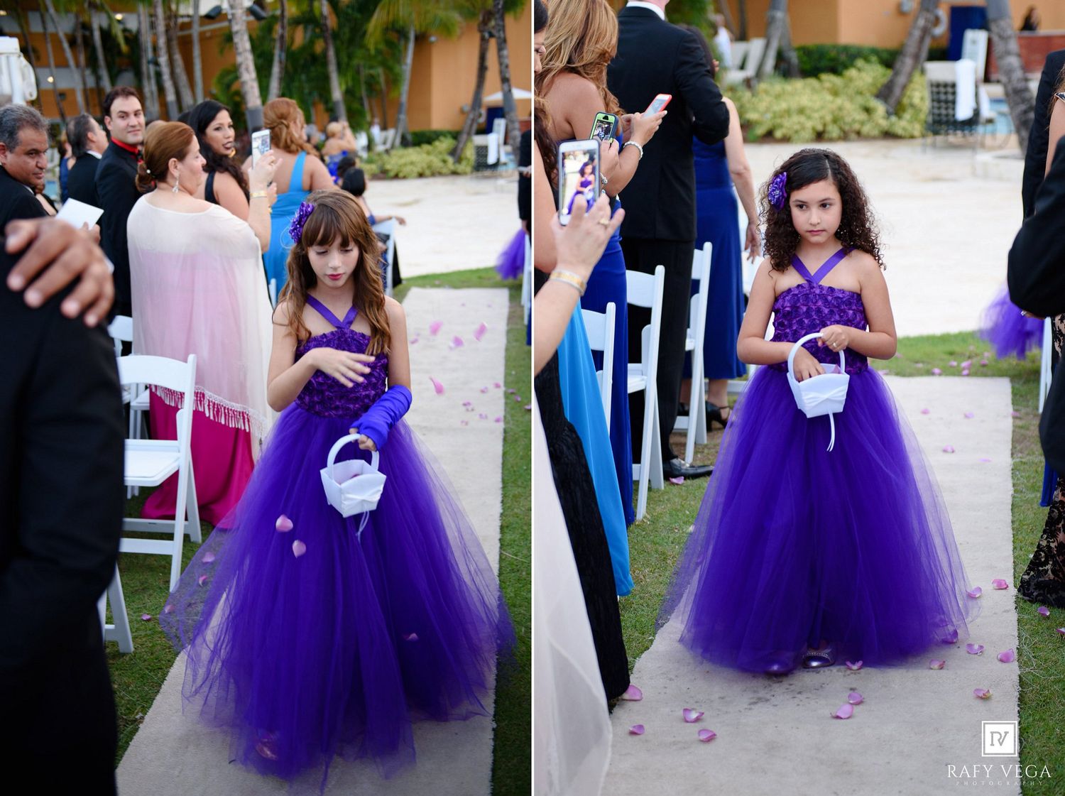 Young flower girl in purple tutu dress walks down outdoor wedding aisle scattering rose petals.