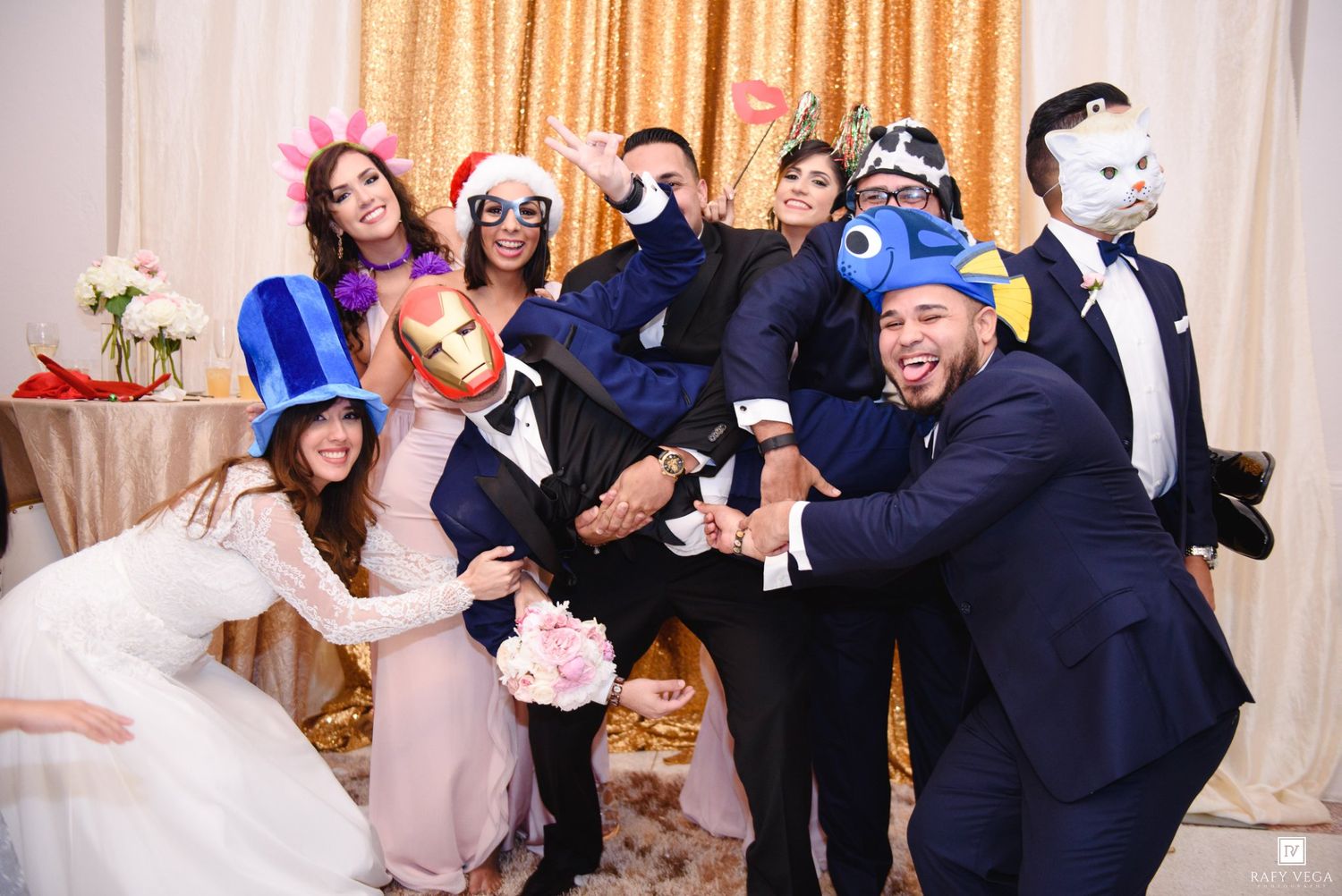 Bride and groom pose with guests wearing colorful photo booth props at wedding.